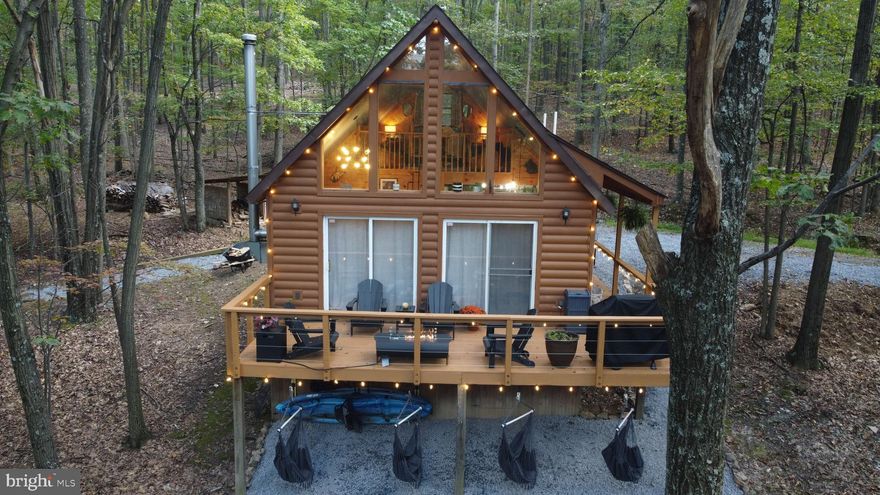 Welcome to your dream retreat in the heart of nature! This charming ALMOST 10-acre  (9.73) cabin is nestled in the woods of a gated community and offers a serene escape for guests seeking tranquility. Currently operating as a successful Airbnb, this 2 bedroom, 1 bath income-generating property has undergone a complete remodel and comes fully furnished for your convenience. The property offers the perfect blend of rustic charm and modern convenience. Step inside to discover a haven of comfort and style.  The spacious living area boasts plush sofas and armchairs arranged around a crackling fireplace, perfect for cozying up with a good book from the extensive library or enjoying a board game with loved ones.  The cabin features a state-of-the-art two-headed wifi control Mini split HVAC system (20k BTU and 30k) to ensure optimal comfort year-round. The heart of the home, the newly designed custom kitchen, showcases new appliances including a stove, microwave,  fridge, and dishwasher, making meal preparation a breeze. The fully-equipped kitchen beckons culinary adventures, complete with gleaming stainless steel appliances, ample counter space, and a selection of cookware and dishes to satisfy even the most discerning chef. When it's time to retire for the night, you'll find comfortable organic bedding and soft linens in each of the thoughtfully appointed bedrooms, ensuring a restful night's sleep.  And for those who prefer the fresh air, a spacious outdoor patio set furnished with comfortable seating and a grill offers the perfect spot for al fresco dining or simply soaking in the natural beauty that surrounds you. N0 detail has been overlooked in this renovation. Every detail has been meticulously attended to, from the heated/insulated utility room in the crawl space to the on-demand electric hot water system and triple-filtered water line. Say goodbye to worries about plumbing issues, as the property features 100% new heated PEX plumbing lines.  With the electrical panel upgraded to accommodate additional circuits on the 200-amp service, rest assured that this cabin is equipped for modern living.  But the amenities don't end there – adventure awaits just steps from your door, with kayaks ready to launch into the waters of the nearby river,  Only 30 minutes to Downtown Berkeley  Springs and Great Cacapon State Park.  After a day of outdoor excitement, unwind and gather around the fire pit for s'mores and stories beneath a canopy of stars.  With every detail carefully considered, from the cozy furnishings to the outdoor recreational equipment, this cabin offers the perfect retreat for making lasting memories and embracing the beauty of nature in comfort and style.   If you're seeking a weekend getaway or a permanent retreat, this remodeled cabin in the woods offers the perfect blend of comfort, convenience, and tranquility.  With its secluded location, modern amenities, and income-generating potential don't miss your chance to own this slice of paradise!  Seller to close with Cardinal Title.