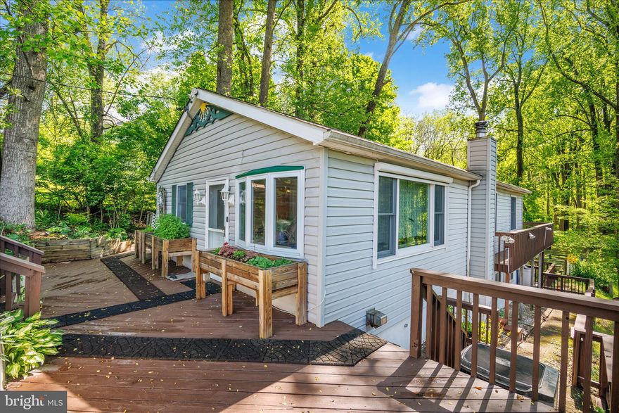 Tucked in near the end of a quiet one-lane road, this 3-bedroom, 2 full bath ranch home offers a peaceful, wooded setting on a half-acre lot backing to the Patapsco State Park and then the river beyond.  Surrounded by mature trees, the property feels like a private retreat with frequent sightings of deer, birds, and other native wildlife, while still very convenient to everyday amenities.

On the main level, you'll find a bright table-space kitchen with ample cabinetry and workspace, opening to the sunny comfortable living room, which could easily be used as a dining room/living room combo. The three bedrooms are on this floor, along with a full bathroom and then access from the two back bedrooms to the upper level deck to enjoy the beautiful views in the back, The finished lower level is a very spacious family room with a cozy working woodstove and more than a cord of seasoned oak firewood. along with a generous eating area, creating a warm and inviting space for relaxing, hobbies, or guests.  There is also a second full bathroom on this level, along with the laundry room and a tool/storage room as well.

Outdoor living is a standout with an expansive two-level deck overlooking the trees—perfect for enjoying the natural surroundings or entertaining. You'll enjoy the thoughtfully landscaped property, featuring abundant flowering shrubs and perennials, enhancing the natural beauty throughout the seasons. The wooded lot offers privacy, space to explore, and a true connection to nature.

Vinyl siding exterior. Roof replaced approximately 2013.  Welcome home!