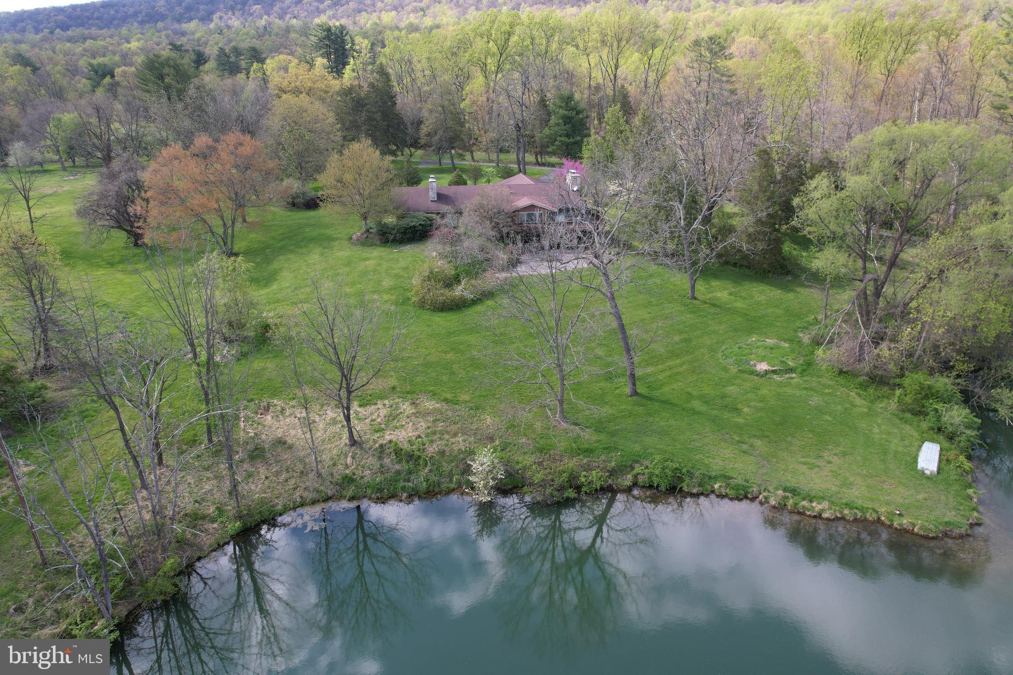 Don’t miss out on this unique opportunity! This property has it all: endless views of nature on 180 acres, a beautiful stone ranch home that needs some TLC and personal touches, two car garage plus 4 bay storage garage for all the big toys, two full kitchens, nice size bar and pool table in family room perfect for entertaining, 3 large bathrooms, lots of windows to take in the sunlight, hardwood floors, tons of storage and closets, lots of built-ins for keeping your treasures safe, skylights at just the right places, vaulted ceilings to make a statement, a huge craft/hobby/workout room, large utility and (more storage) room, an elevator for easy access to both levels, three ceiling-to-floor stone fireplaces, ceiling to floor stone waterfall with spiral staircase, a large scenic pond for boating and fishing, a wrap around deck and patio overlooking the pond, mountain and fields, your very own orchard with various fruit trees, circular driveway with extra parking for RV or other luxury toys. All this and more; you have to see it to believe it. Proof of Funds required for additional information and a showing.