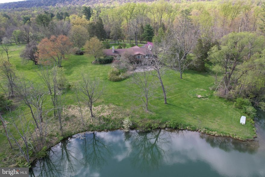 Don’t miss out on this unique opportunity!  This property has it all: endless views of nature on 180 acres, a beautiful stone ranch home that needs some TLC and personal touches, two car garage plus 4 bay storage garage for all the big toys, two full kitchens, nice size bar and pool table in family room perfect for entertaining, 3 large bathrooms, lots of windows to take in the sunlight, hardwood floors, tons of storage and closets, lots of built-ins for keeping your treasures safe, skylights at just the right places, vaulted ceilings to make a statement, a huge craft/hobby/workout room, large utility and (more storage) room, an elevator for easy access to both levels, three ceiling-to-floor stone fireplaces, ceiling to floor stone waterfall with spiral staircase, a large scenic pond for boating and fishing, a wrap around deck and patio overlooking the pond, mountain and fields, your very own orchard with various fruit trees, circular driveway with extra parking for RV or other luxury toys.  All this and more; you have to see it to believe it. Proof of Funds required for additional information and a showing.