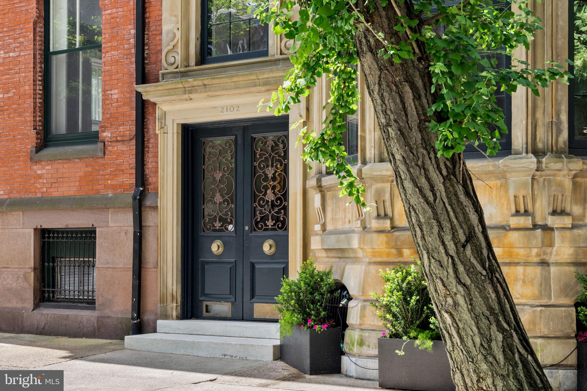 Move in Ready! This exquisite combination of historic preservation and modern convenience is one of Rittenhouse’s most prized locations. The must-see gourmet kitchen is light filled and features two pantries, dual sinks, two ovens, dishwashers and a subzero refrigerator. This family space features a large dining area, media room/den, a full bathroom, alongside a sundeck offering 360-degree views and grilling area. 5,752 square feet on four levels sits atop the daylight basement of which includes a laundry, craft area, exercise space, additional storage, and a 650 bottles wine cellar. All five levels are served by an elevator. All systems, including HVAC, and security, have been expertly maintained and upgraded.
The owner’s level has three stunning rooms, each with a marble fireplace. The primary bedroom at the front has a large bay window and an ensuite bathroom with steam sauna. The second bedroom room, currently used as a dressing room, also has an ensuite bath. These two rooms share an impressive set of closets. The third room, with southern exposure, is an exquisite library with magnificent built-in bookcases and featuring a Tiffany chandelier.
There are three large additional bedrooms, each with marble fireplace and its own bathroom. There is a subsidiary laundry serving these three rooms. Extensive closets throughout are certainly a unique feature for a home of this era.
2102 Spruce Street, a marvel of historic preservation combined with modern comfort and convenience, is available for sale for only the fourth time in 157 years. Known as the Cadwalader Mansion, the home is a five-story wonder, on a lot measuring 22 feet in width and 150 feet in depth, originally built as a wedding gift for John Cadwalader and Mary Fisher, both from prominent families in Philadelphia. It is one of the best-preserved historic properties in Rittenhouse Square and served as the French Consulate during the 1950’s and 60’s. The mansion showcases French Second Empire architecture, distinguished by its multicolor mansard roof on the fourth level, reflecting Parisian influences. Unlike the prevalent brick colonial and brownstone townhomes in the Rittenhouse Square neighborhood, the mansion’s front façade is made of limestone, allowing for larger windows and enhancing the building’s height.
The primary entrance opens to an enclosed marble entryway with steps leading to the main level, a luxury at the time as it offered shelter from the elements before entering the house. The original brass fret-work doors, lock, and key have been preserved. Inside, the first floor, elevated five feet above street level, features 14-foot ceilings adorned with moldings reconstructed from the original plaster molds and inlaid oak floors. Throughout, high ceilings and extremely impressively-scaled rooms are complemented by extraordinary detail. The main level includes a large living room with a marble fireplace and a Tiffany crystal chandelier, a central gallery, and a dining room overlooking a parklike landscaped garden that connects to the carriage house, now a two-car garage. The dining room features one of three custom gold wash mirrors with a large “C” for Cadwalader. There is also a fully equipped catering kitchen and bar. A silver safe is hidden behind a matching door. The inlaid floors continue throughout, complemented by expansive windows and skylights that create a warm and sunny atmosphere. With an eye to the legacy of the design, only the very top-quality methods and materials have been selected.