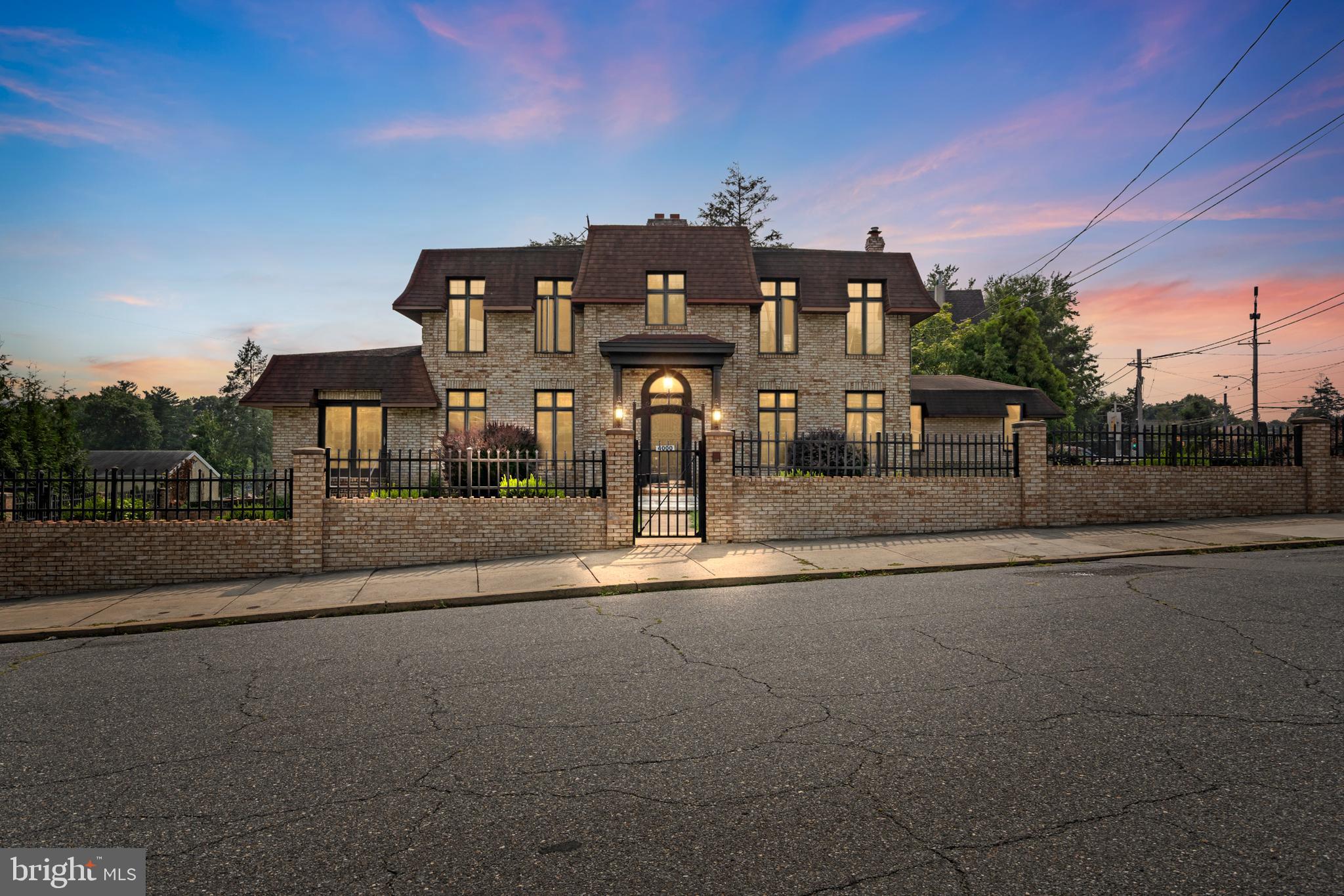 Behind a private gated entry, this stately brick residence offers the perfect balance of elegance and everyday comfort. With 4 bedrooms, 3 full bathrooms and a 1/2 bathroom, and a versatile layout, it’s designed to accommodate both family living and sophisticated entertaining. The main level showcases a grand living room with custom woodwork, fireplace, and chandeliers, a formal dining room, and a spacious eat-in kitchen with exposed brick archways, granite center island, and modern stainless steel appliances. A bright Florida room with floor-to-ceiling windows provides a year-round retreat for relaxation or family gatherings. Also on the first floor, a private bedroom with full bath is ideal for guests or multi-generational living. Upstairs, you’ll find three generously sized bedrooms and two full baths, including a primary suite with private bathroom and a conveniently located laundry area. The lower level features a 3-car garage with outside access, offering ample storage and utility space. Outdoors, the brick exterior, wrought-iron fencing, and landscaped grounds create a striking presence and private setting.