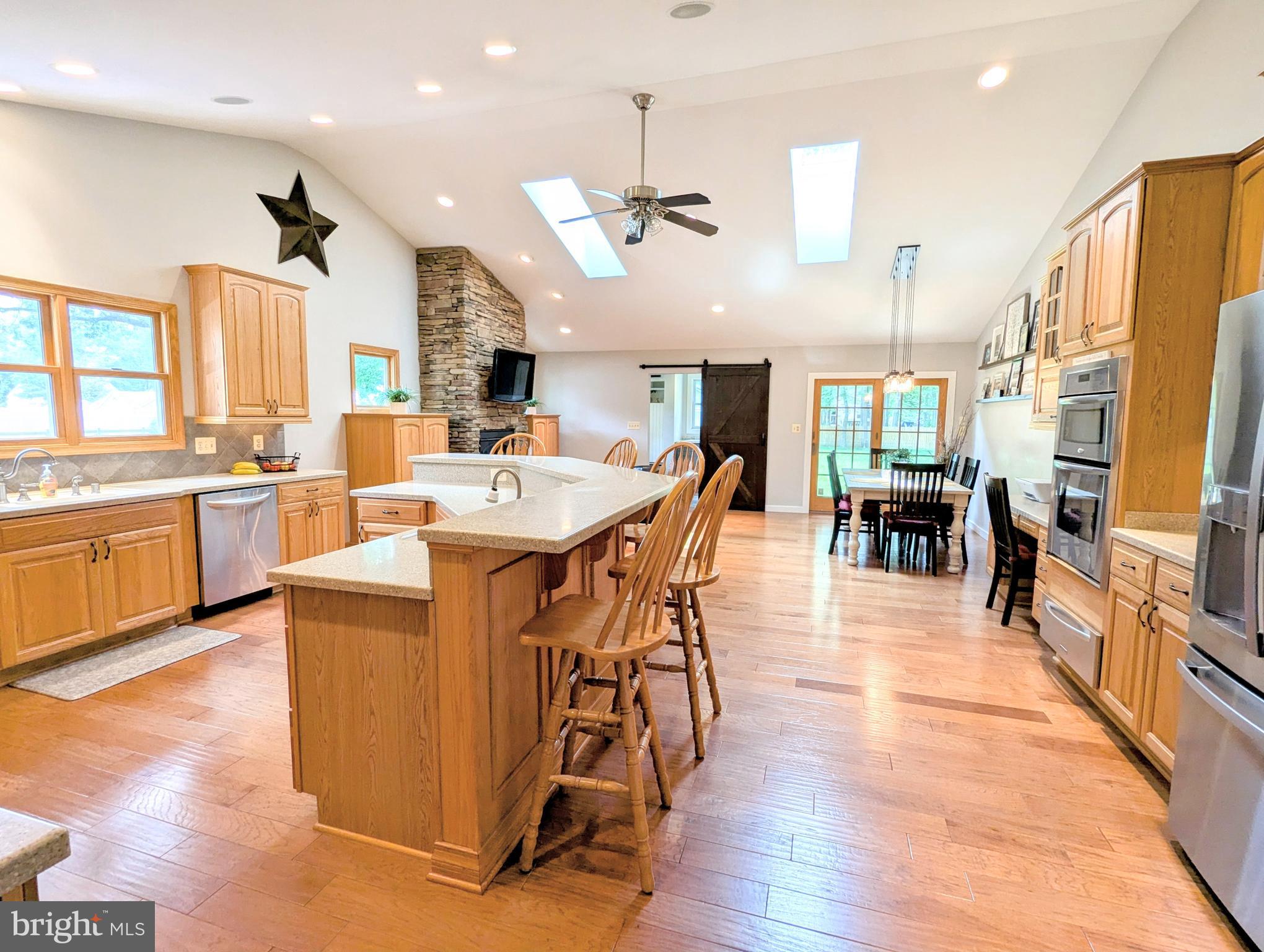 Arguably one of the most stunning homes in Cloverfields! This beautifully expanded 3,268 sq ft residence features a breathtaking custom kitchen addition that’s tailor-made for family gatherings and entertaining. With over 600 sq ft of thoughtfully designed space, you'll enjoy vaulted ceilings, skylights, a spacious dining, and a stacked-stone fireplace in the cozy sitting area.
The kitchen is a true showstopper—complete with hardwood floors, built-in desk, and a massive island perfect for bar stools, wall oven, six-burner cooktop, dishwasher, microwave and upgraded refrigerator. No detail has been overlooked: custom spice racks, double trash pull-out, built-in recycling center, warming drawer, whole house & exterior sound system w/individual room controls, and more—all designed to enhance your daily living and culinary experience. Conveniently located off the kitchen is a mudroom featuring a second refrigerator, half bath, and stylish barn-door storage, adding both function and flair.
And that’s not all… Step onto the welcoming covered front porch and into a spacious living room that sets the tone for the rest of this beautifully designed home. Just a few steps down, you'll find a generously sized family room complete with a fireplace, stylish bar for entertaining, and two comfortable bedrooms—perfect for guests, teens, or multi-generational living.
A few steps up from the main level leads you to two additional roomy bedrooms and the luxurious primary suite. The primary bedroom offers a peaceful retreat, while the new en-suite bath features stylish finishes and thoughtful touches. You'll also find a brand-new laundry room conveniently located on this level. All five bedrooms are equipped with walk-in closets, providing abundant storage. Custom bath cabinets and closets include built-in outlets, keeping cords neatly tucked away while your devices charge.
Additional upgrades include a new 80-gallon water heater and an advanced HVAC system with damper-control thermostat for efficient, customizable comfort throughout the home. This home is more than move-in ready—it's a thoughtfully curated space where every feature was designed with comfort, convenience, and lifestyle in mind.