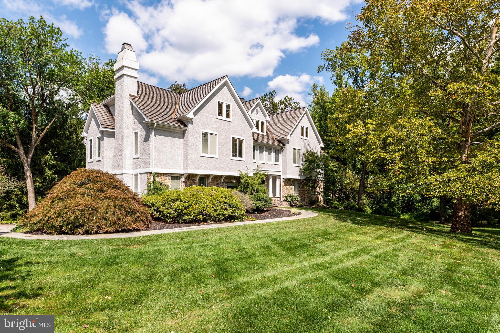 Welcome to Thornbrook — a light-filled, beautifully updated home in the heart of Bryn Mawr. Offering 5 bedrooms, 4.5 baths, and a flexible floor plan, this residence is thoughtfully designed for comfortable daily living and effortless entertaining.
Enter through double doors to a dramatic two-story room — currently appointed as a dining room but equally suited for a family room, entertaining space, or other use to fit your lifestyle — with doors opening to an oversized wraparound deck. Off the foyer, the spacious living room with fireplace creates a warm, welcoming setting. A bar/butler’s pantry connects the living room to a private study (optional 6th bedroom) with a full bath.
The dining/kitchen zone flows into a bright eat-in kitchen, mudroom, and powder room. Just beyond, the family room features a second fireplace and custom built-ins, offering a cozy spot to relax.
Upstairs, the primary suite occupies its own wing with a generous bedroom, large walk-in closet, and beautifully updated en-suite bath. Four additional bedrooms and two full baths provide abundant space for family and guests. A large walk-up attic offers potential for a gym, playroom, or additional flex space.
The finished lower level includes a fireplace, ample storage, and room for recreation or work. Additional highlights: 3-car garage, cedar roof, new heater and A/C, whole-house generator, and remodeled baths — all updated in 2019.
Designed by Neil Rambert, Architect, Thornbrook combines timeless architectural integrity with modern livability. Rambert’s practice begins with an “architectural history” study to ensure each home harmonizes with its setting while meeting contemporary lifestyle needs. Known for blending scholarship with practicality, his work seamlessly integrates classic Main Line character with fresh, functional design.
Conveniently located near top schools, major roadways, shopping, and dining, this home blends architectural pedigree with thoughtful updates in a prime Bryn Mawr location.