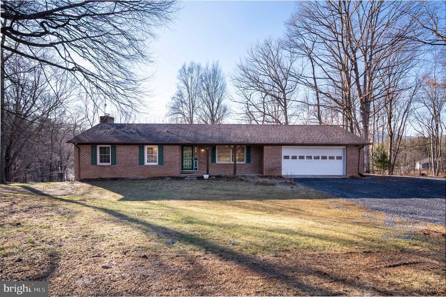 One-level living on 5 private acres with over 3,100 finished square feet—offering exceptional space both inside and out. This 4-bedroom, 3-full-bath home features a stunning 22x30 family room addition with vaulted ceilings, recessed lighting, and gleaming hardwood floors. The spacious kitchen offers abundant cabinetry, generous counter space, a breakfast bar, and breakfast area—perfect for everyday living and entertaining. Main-level laundry adds convenience. The primary suite includes a private bath and large closet, with two additional bedrooms and a full bath completing the main level. Enjoy over 1,000 feet of wraparound decking with gazebo and concrete patio, ideal for outdoor gatherings, plus seasonal mountain views. The freshly painted lower level includes a family room with wet bar, brick hearth fireplace with wood-stove insert, an additional bedroom, full bath, and home office or gym. Oversized 28x28 two-car garage with workshop/storage area, ample driveway space, and room for additional parking. Peaceful country setting close to the Shenandoah River, Andy Guest State Park, hiking trails, wineries, and more. Approximately 1.5 miles to Skyline Drive and just 8 minutes to town conveniences. All paved roads with easy access. Roof is 10 years old.