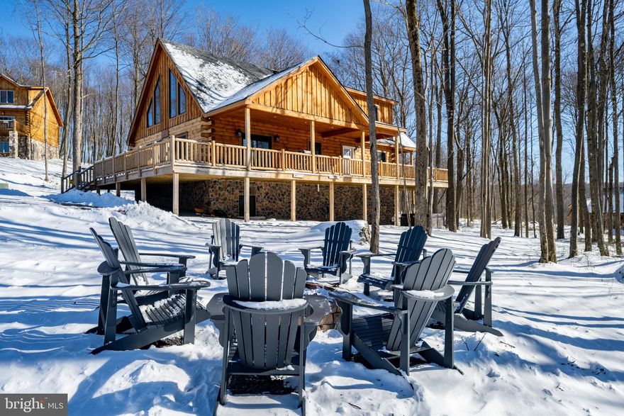 Private wooded setting in North Camp Ridge, just minutes from Wisp Resort, Fork Run, and Deep Creek Lake. This 5-bedroom, 5.5-bath log chalet offers three finished levels with an open-concept main floor and an oversized loft above. Rustic character meets modern finishes throughout, including a kitchen with stainless steel appliances, custom hardwood cabinets, granite countertops, and bar seating. A stacked stone fireplace anchors the main living space, with abundant glass pulling in natural light. The walk-out lower level adds a second living area and game room. Five en-suite bedrooms support flexible use as a vacation rental or private retreat. Outdoor features include a wrap-around deck, hot tub, and fire pit. A well-rounded mountain home with space, privacy, and close access to year-round amenities. Call today for details!