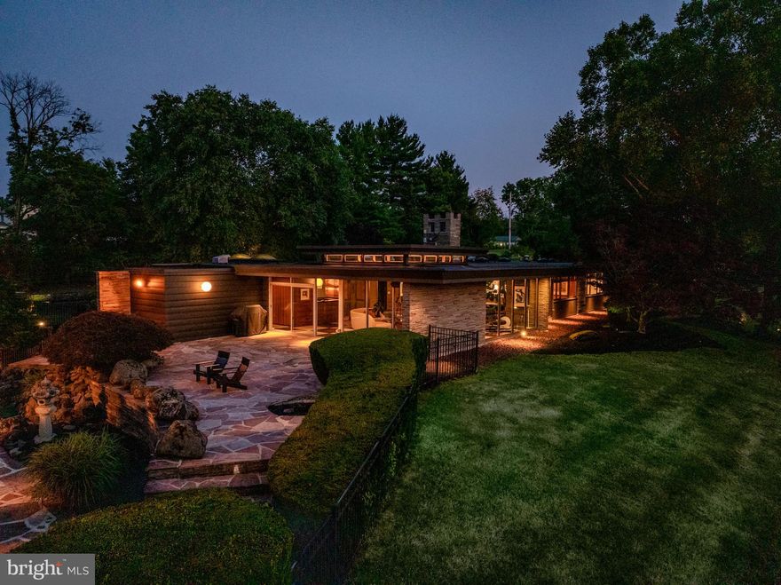 Once-in-a-lifetime opportunity to own an exceptionally designed mid-century modern retreat thoughtfully sited on 6.5 private acres overlooking Skippack Valley. Embracing the style and vision of Frank Lloyd Wright, architect Walter Wisznia artfully positioned this single-level sanctuary for optimal views of the landscape and to coexist with the surrounding natural beauty. Both the home and iconic pool house skillfully bring the outdoors in through floor-to-ceiling expanses of glass. The property is enhanced by a magazine-worthy pool, curved pergola, Japanese-inspired grounds and contemporary aesthetic.
Beautifully updated and reverently maintained, this 5,300+-square-foot residence is the ideal destination for architecture buffs and those with a passion for indoor-outdoor living and entertaining. The home’s living room is a showstopper featuring a double-pitched roof lined with clerestory windows, black and white marble floors, and mid-century-appropriate natural materials, including swaths of stacked stone and wood details in teak, mahogany, cedar, and oak. Relax and entertain in the open-plan living and dining rooms, naturally divided by a two-sided fireplace, offering an exceptional space for entertaining complete with an adjacent oversized bar lounge and breathtaking views. The kitchen impresses with sleek Poggenpohl cabinetry, granite countertops, and upscale Miele appliances.
Elegant living and entertaining continue in the outdoor spaces, where two levels of expansive flagstone patios stretch to the resort-sized swimming pool and curved pergola. Imagine peaceful afternoons and evenings spent surrounded by meticulously tended landscaping, large lawns, a rock garden and never-ending Skippack Valley vistas. The almost 500 sq ft temperature-controlled pool house does double-duty as a party room or guest house complete with a large circular wet bar, full bathroom, changing room, and rear deck with hot tub.
The main home's luxurious accommodations begin with a private and sprawling owner's suite featuring a king-size bedroom, a skylit ensuite spa bathroom with a 12-piece Kohler luxury shower system, and rows of generous closet space, including a custom walk-in. The attached bonus room is ideal as a gym, media room, or private office with stained glass windows. Two large secondary bedrooms and a full hall bathroom complete this wing. A second wing of the home includes an additional private bedroom suite with a full bathroom, which is perfect for guests or staff. The massive family room is a perfect gathering spot featuring beamed ceilings, custom built-ins, Knoll Maharam wallcoverings and original leather wallcoverings. A breakfast room, laundry room, powder room, and oversized storage room complete the beautifully planned layout. Outside a winding driveway, motor court, and five garaged spaces provide plenty of parking for car buffs, while the stone façade and walls of glass reinforce the midcentury style of this sophisticated hideaway.
The tranquil location is surrounded by national and state parks, golf courses, and numerous local shopping centers. King of Prussia and Philadelphia are within easy reach, and New York City is just two hours away.