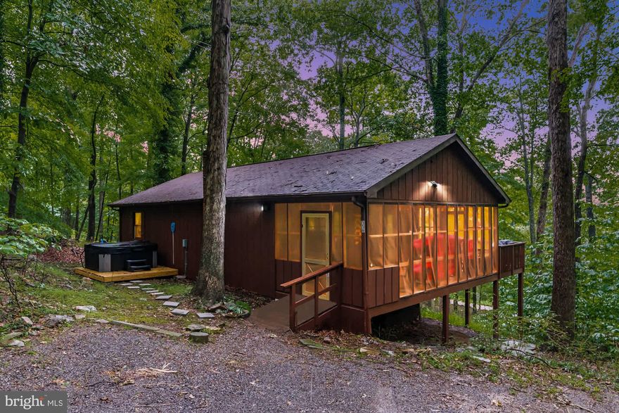 Tucked away in the WV woods surrounded by old-growth forest, this 2-bedroom, 1-bath cabin offers a welcoming open floor plan and living area with a cozy wood stove, wood plank ceilings, a large screened-in porch, & fast fiber Internet/WiFi.  Outside you’ll also find a deck, fire pit, and brand new hot tub.  Professionally designed with all new furniture and modern decor.  Just a short 5-minute drive from the cabin, you’ll also have private community access to the Cacapon River – great for tubing, fishing, or kayaking.  The seller spent over $30,000 upgrading & furnishing the property.  As a vacation rental it has generated $38,000 in the past year ($133,000 over the past 3 years!), and can come with an existing property manager and cleaner.  Hot tub and furniture optional, available for purchase.  See seller docs for a summary of rental history and financials.  $1,000 buyer credit if you continue using the same property manager.  Perfect vacation home or investment property!