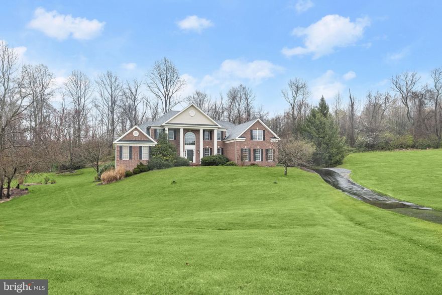 Welcome to this stunning Toll Brothers Cumberland Model Colonial, nestled on a private 1.32-acre lot boasting nearly 5,000 sq. ft. of luxurious living space. The all-brick front with a stately portico welcomes you into the 2-story foyer, featuring hardwood flooring, architectural columns, and accent molding. Recent updates include the roof, primary bath, appliances, terrace, landscaping, furnace, deck, spa, well pump, garage, chimney, ceiling fans, patio, and more, ensuring modern comfort and style throughout. The gourmet kitchen is a chef's dream, offering an entertainer's island breakfast bar, granite countertops, rich wood cabinetry, and stainless appliances, including a double oven. The huge family room features a high cathedral ceiling, an oversized, wood-burning fireplace, and a second staircase to the upper level. A bright and airy sunroom with a vaulted ceiling provides deck access. The main level primary bedroom suite includes a sitting room with a gas fireplace and cathedral ceiling, along with 2 walk-in closets and a luxury primary bath with a soaking tub, separate shower, and two vanities. Upstairs, there are 2 bedroom suites with full baths and 2 bedrooms with a dual-entry full bath. Customize the full, walkout lower level to fit your exact needs. Outside, enjoy outdoor living in your own private retreat on the expansive deck under a pergola, admiring the professionally landscaped yard with a waterfall and firepit. Don't miss the opportunity to make this exceptional property your dream home!