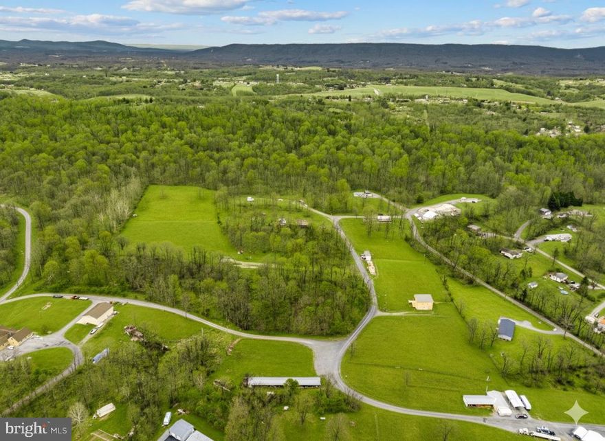 Own a piece of entertainment history on 16.209 unrestricted acres, the former Triple B Arena, celebrated for rodeos, live concerts, and large-scale events, including performances by Trace Adkins. Located just minutes from downtown Berkeley Springs, a destination known for its historic spas, seasonal festivals, arts and culture events, restaurants, and year-round tourism, the property is well-positioned to attract consistent crowds for outdoor recreation, entertainment, and community events. Purpose-built for large audiences with substantial infrastructure and ample parking, it’s ideal for a brewery, event venue, wellness retreat, small-scale development, auction facility, or private estate with space for animals, equipment, or a business. At the core of the property is a professionally constructed performance stage designed to support touring acts and high-capacity events. The 30’ x 40’ stage includes two sound wings and is powered by an impressive 800-amp service dedicated exclusively to stage operations, with panel boxes for direct hookups and 120-volt receptacles spaced throughout. Beneath the stage are two finished dressing rooms complete with lighting, mirrors, and restroom access, along with a 10’ x 30’ storage room. Behind the stage, tour bus parking offers 50-amp shore power connections and sewer hookups, a rare feature for a property of this kind. The arena footprint measures approximately 250’ x 300’ and is fully illuminated for nighttime use. Supporting infrastructure includes a high-capacity septic system engineered to accommodate crowds of up to 5,000, as well as treated public water with chlorination suitable for large-scale events. A separate restroom and office building provides extensive facilities, including multiple men’s and women’s restrooms—all handicap accessible—with modern fixtures, hot and cold water, and air dryers. Above, a second-floor office and VIP area overlooks both the arena and stage and includes a PA system capable of broadcasting announcements throughout the entire complex. Food and beverage operations are supported by a 16’ x 32’ concession building featuring a commercial hood system, substantial electrical capacity, LP gas plumbing, and multiple service windows. The venue previously operated with an on-premises beer license, adding flexibility for hospitality-focused uses. Additional improvements include multiple support structures, dressing rooms beneath the bandstand, a rented mobile home, and expansive open fields suitable for parking, expansion, or alternative development. This property presents a compelling opportunity to leverage an established legacy while creating something entirely new in a prime location near Berkeley Springs. For more information or detailed comments regarding the property’s infrastructure, please reach out to schedule a private consultation.