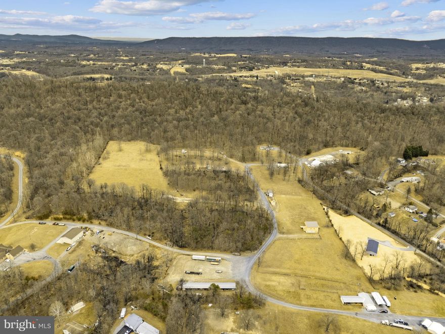 Own a piece of entertainment history on 16.209 unrestricted acres, the former Triple B Arena, celebrated for rodeos, live concerts, and large-scale events, including performances by Trace Adkins. Located just minutes from downtown Berkeley Springs, a destination known for its historic spas, seasonal festivals, arts and culture events, restaurants, and year-round tourism, the property is well-positioned to attract consistent crowds for outdoor recreation, entertainment, and community events. Purpose-built for large audiences with substantial infrastructure and ample parking, it’s ideal for a brewery, event venue, wellness retreat, small-scale development, auction facility, or private estate with space for animals, equipment, or a business. At the core of the property is a professionally constructed performance stage designed to support touring acts and high-capacity events. The 30’ x 40’ stage includes two sound wings and is powered by an impressive 800-amp service dedicated exclusively to stage operations, with panel boxes for direct hookups and 120-volt receptacles spaced throughout. Beneath the stage are two finished dressing rooms complete with lighting, mirrors, and restroom access, along with a 10’ x 30’ storage room. Behind the stage, tour bus parking offers 50-amp shore power connections and sewer hookups, a rare feature for a property of this kind. The arena footprint measures approximately 250’ x 300’ and is fully illuminated for nighttime use. Supporting infrastructure includes a high-capacity septic system engineered to accommodate crowds of up to 5,000, as well as treated public water with chlorination suitable for large-scale events. A separate restroom and office building provides extensive facilities, including multiple men’s and women’s restrooms—all handicap accessible—with modern fixtures, hot and cold water, and air dryers. Above, a second-floor office and VIP area overlooks both the arena and stage and includes a PA system capable of broadcasting announcements throughout the entire complex. Food and beverage operations are supported by a 16’ x 32’ concession building featuring a commercial hood system, substantial electrical capacity, LP gas plumbing, and multiple service windows. The venue previously operated with an on-premises beer license, adding flexibility for hospitality-focused uses. Additional improvements include multiple support structures, dressing rooms beneath the bandstand, a rented mobile home, and expansive open fields suitable for parking, expansion, or alternative development. This property presents a compelling opportunity to leverage an established legacy while creating something entirely new in a prime location near Berkeley Springs. For more information or detailed comments regarding the property’s infrastructure, please reach out to schedule a private consultation.