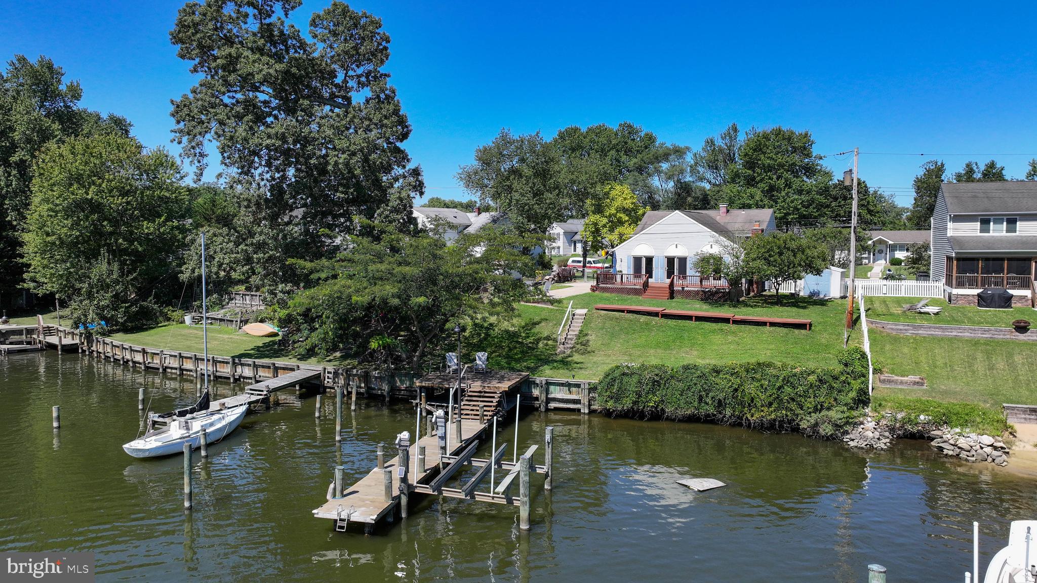Nestled peacefully on the shores of Rock Creek off the Chesapeake Bay, this lovely split-level home is the ideal boater's haven for sailors and power boaters alike. The open water views are beautiful, with approximately 78' of bulkheaded shoreline. The private pier has deep water with typical 6' depth, 12.5k lb boat lift (new in 2018) and an additional slip to accommodate a wide beam. A deck cantilevered over the water's edge is the perfect place to enjoy the day's catch. Enter the home into a spacious living room with hardwood floors. Just beyond is a kitchen with room to dine-in, overlooking a large great room addition on the waterfront side with a brick hearth fireplace, beamed, vaulted ceiling, hardwood floors and sliders to the huge waterfront deck. Two full bathrooms have been tastefully updated. The HVAC was very recently replaced (2025). The pier and waterfront deck were rebuilt in 2017. The concrete driveway extends to the rear yard offering ample parking or additional patio space for entertaining and a 2nd entrance into the great room. Rock Creek is a sailor's delight with deep water (typical 12 ft in the middle of the creek off of the private dock and to the mouth). Located within minutes of the mouth of Rock Creek and the Chesapeake Bay, in just 25-50 minutes, boat to Baltimore's Inner Harbor, Canton, Fells Point, Locust Point, Annapolis or venture across the Bay to Rock Hall & Kent Island! Rock Creek is home to two favorite local waterfront restaurants you can boat to within minutes. This lot and home are primely positioned to enjoy the Maryland waterfront lifestyle in one of the east coast's best boating destinations AND an easy commute to Baltimore, Annapolis or DC! Make an appointment today and discover everything the Peninsula Life has to offer! Professional and drone photos and video coming soon.