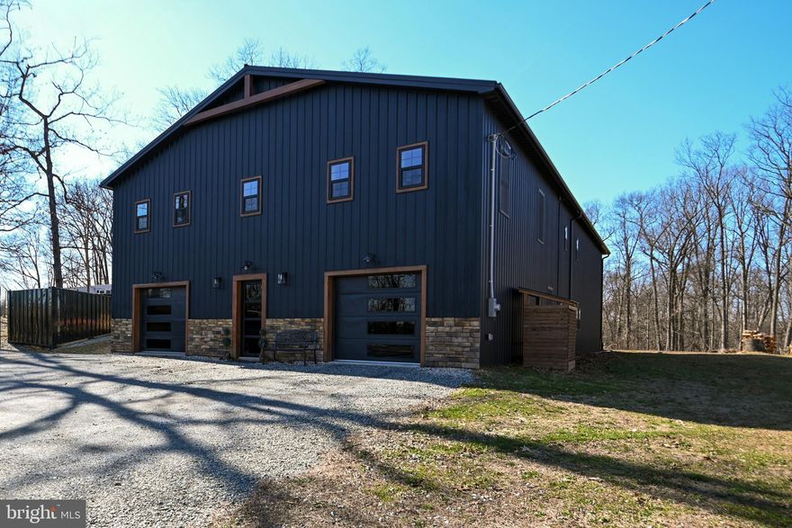 Imagine owning a true showstopper! This 5,000 sq. ft. custom Amish-built barndominium offers 3,500 sq. ft. of beautifully designed living space, blending everyday comfort with unforgettable entertaining.
An open-concept great room seamlessly connecting kitchen, dining, and living areas is the heart of the home. Through double barn doors awaits the ultimate centerpiece: a 1,000 sq. ft. ballroom with soaring 18-foot ceilings, exposed wood trusses, stage lighting, a projector, wood stove, basketball hoop, and even a rock-climbing wall. A 12-foot-wide glass garage door opens to the flat backyard, creating an effortless indoor to outdoor flow. With its durable concrete floors, this flexible space is ideal for showcasing a car collection, operating a workshop, hosting roller-skating events, or running a home-based business.  The home features six spacious bedrooms and three full baths, including a convenient first-floor queen bedroom with a tiled bath and rain shower, ideal for guests, extended family, or an au pair.
The private owner’s wing includes two oversized bedrooms and a spacious primary suite with a king-sized bedroom, large walk-in closet, and a luxurious bath featuring dual vanity, walk-in shower, and jetted soaking tub. A billiard room overlooks the grand entertaining space below.
Designed for durability and efficiency, the home includes superior finishes, tiled baths, tankless gas water heater, energy-efficient HVAC, and high-quality metal roof for long-term peace of mind. Sleek black stainless steel appliances, continuous plank flooring, color-changing smart lighting, exterior security cameras, and a smart thermostat create a modern, efficient living experience fully controlled from your mobile device.
Car enthusiasts and hobbyists will appreciate the his-and-her garages, plus parking for up to 16 vehicles, RV, boat or large equipment.
Situated on a private 0.7 acre wooded lot in Felton, York County, with an easy commute to Maryland, this one-of-a-kind property offers rural charm without sacrificing convenience. Enjoy nearby breweries, the Heritage Rail Trail, Gettysburg, Hershey, Lancaster’s Amish countryside, local parks, and shopping outlets, all just a short drive away.
Call today for more details on this exceptional opportunity!