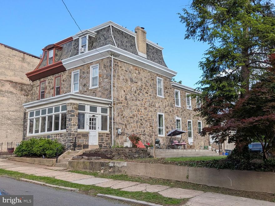 Some opportunities announce themselves quietly. 3504 and 3508 Ainslie Street is two separately deeded lots selling together, and the possibilities are genuinely exciting. If you need a nudge to move quickly, consider this: of the three most recent sales on this block, one never even hit the market, and the other two were gone in a day. Don't be the one who drove by and waited too long.
Keep them as one spectacular property with a yard and parking that would make your neighbors jealous. Develop 3508 into an additional dwelling and create your own private compound. Or hold the extra lot and decide later. The optionality alone is worth the conversation.
The main house at 3504, built circa 1876, sits on the coveted sunny side of Ainslie Street, and the southern exposure fills every room with natural light in a way that has to be experienced to be appreciated. Next door at 3508, a wide, fully separate lot currently handles the parking (4+ cars with room to spare) and yard. This is not a narrow strip of land we're talking about. It is one of the largest side situations on the block.
Enter first through a generous enclosed three-season sunroom before stepping into the front vestibule. To the right, the living room greets you with a decorative fireplace and the kind of historic Victorian character that simply doesn't get built anymore: plaster crown molding, soaring baseboards, intricate original doors and trim throughout. The house has excellent bones, and it shows.
Past the living room, the floor plan opens up into a beautifully renovated kitchen and dining room. The kitchen was recently renovated, and it is a thoughtful, clever design featuring soaring ceilings and an exceptional amount of cabinetry for storage. The original back staircase is intact and connects off the kitchen, a detail that period house lovers will appreciate. Behind the kitchen you'll find the laundry area and a full first-floor suite, a large bedroom with its own full bathroom, ideal for guests, a private home office, or a flexible live-work setup.
Upstairs on the second floor, a large front bedroom anchors one end of the floor. In the middle sits a full bathroom and a kitchenette or potential wet bar area. At the rear, a second large bedroom functions as a true suite with loads of storage and a fully renovated full bathroom. Three full bathrooms across the first two floors is a rare find in a house of this vintage.
The third floor adds two more generously sized bedrooms, bringing the total to five bedrooms across the home. Whether that means dedicated work-from-home space, room for everyone under your roof, or simply the luxury of never fighting over a room again, the third floor delivers. And below it all, a full unfinished basement with 8-foot ceilings offers serious additional potential, whether that's storage, a workshop, or something more.
East Falls is a tree-lined, river-adjacent neighborhood with a strong village identity and serious urban convenience. The Regional Rail station is a three-minute walk, putting Center City within easy reach. For dining and nightlife, In Riva, Fiorino, LeBus, Wissahickon Brewing, and Billy Murphy's are all nearby, with Vault + Vine and Thunder Mug handling the coffee. The Schuylkill River Trail and Wissahickon Valley Park are practically out the front door.
