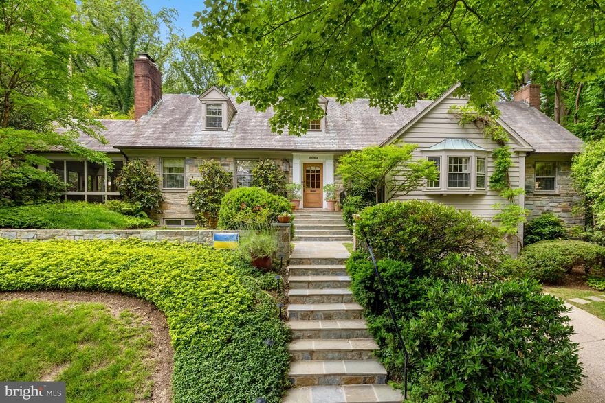 Nestled in the heart of Spring Valley, 5060 Overlook Road NW is a stately Cape Cod that seamlessly blends timeless architectural elegance with modern comforts—including a rare main-level primary bedroom suite with two ensuite full baths, making for a total of three full bathrooms on the first floor. Encompassing 5,550 square feet on a generous 0.38-acre lot, this home offers exceptional space, privacy, and presence.

Upon entry, the foyer sets the tone for this gracious residence. To the left, the formal living room invites you in with its wood-burning fireplace and seamless access to a bright screened-in porch—perfect for morning coffee or quiet reading. Flowing naturally from the living room is a charming sitting room that opens into a sunlit breakfast area and a European-inspired kitchen with St. Charles cabinetry. Outfitted with sleek stainless steel appliances, honed marble countertops, and all-white cabinetry, the kitchen exudes modern refinement. From here, the formal dining room is framed by a bay window that bathes the space in natural light. Beyond, the layout unfolds into a library/media room and a family room anchored by a fireplace and built-in wet bar. Surrounded by windows with picturesque views of the lush backyard and stone patio, this space offers a seamless connection to the home’s tranquil outdoor setting.

The lower level expands the living experience with a large game room, a spacious laundry area, a private guest suite with ensuite full bath, and a separate entrance to the exterior—enhancing flexibility and privacy. Additional highlights include a storage room off the attached three-car garage, outfitted with custom shelving and ideal for use as a wine cellar, in addition to the ample attic storage.

Upstairs, the home offers four additional bedrooms and two full bathrooms, each designed with generous closet space and abundant natural light. Two ample linen closets and attic access enhance practicality and complete this level.

Whether hosting grand gatherings or enjoying peaceful moments at home, this residence offers a thoughtful layout, refined details, and a truly special setting in one of Washington, DC's most sought-after neighborhoods.