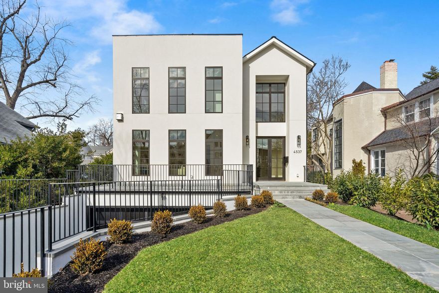 Monument Builders proudly unveils 4537 Lowell St NW, a newly constructed masterpiece that showcases a reimagined Contemporary-style home with 6 Bedrooms, 5 Full Baths, and 2 Half Baths, and an oversized 2-Car Garage. Delivering 6,400 finished SF, this California-style dream home is unforgettable with its and perfectly placed windows, incredible Nano doors that extend the Family Room outside oversized to the expansive yard, and extraordinary hand-picked marble features. A wood-paneled elevator gives access to all 4 floors. The exceptional outdoor spaces include a large patio that pours out into the level yard, two rooftop decks, and a front porch. Nestled in Wesley Heights on coveted Lowell Street, this exciting home sparkles with a desirable southern exposure and a stylish vibe that suits a modern lifestyle.   Intricate custom millwork and herringbone hardwood floors accent the Foyer and the thoughtful floor plan invites you to explore the expert craftsmanship and magnificent quality that is apparent throughout the entire home. Gorgeous sightlines are everywhere, beginning with a striking view from the Foyer that carries directly through the home to showcase a glimpse of the Patio through the rear folding doors. Dramatic 10'+ ceilings make quite the lasting impression as you travel through the main entertaining spaces. The formal Living Room is flooded with natural light through 3 large south-facing windows and the entire space is warmed by a modern gas fireplace.   The Dining Room is dressed in decadent molding and showcases a built-in buffet and secondary access to the huge Pantry. One of the most impressive areas is the Family Room, a space that was designed with intimate gatherings as well as large events in mind. The Family Room is centered by a gas fireplace with a marble slab surround that carries all the way up to the coffered ceilings. A wall of Nano doors dovetails the indoor and outdoor spaces, creating a remarkable atmosphere. The adjoining Kitchen and Breakfast Area are complete with an elegant marble waterfall island, paneled appliances, custom cabinetry, and a large walk-through Pantry.   There are 4 Bedrooms on the First Upper Level, each of which has access to an En-Suite Bath. The Primary Suite is comprised of a spacious Bedroom that overlooks the backyard, two walk-in closets with wall-to-wall custom built-ins, and a luxurious Bath. The Primary Bath boasts a Wet Room with a soaking tub and a shower, a dual vanity, and a Water Closet. The second Bedroom Suite has a walk-in closet and a private Bath. Bedrooms #3 and #4 have tray ceilings and share a "Jack and Jill" style Bath. There is a secondary Laundry Room on this level.   The Second Upper Level is highlighted by 2 Roof Decks and a Party Room with a beautifully designed Bar that houses an Ice maker and a Beverage Refrigerator in a spacious custom-made cabinet. This room has an En-Suite Bath and may also be used as a Guest Suite, Office, or Home Gym. Outdoor deck space makes up approximately half of the top floor footprint, a feature that is not often found but absolutely treasured.  Additional living space is on the Lower Level including a Recreation Room, Bedroom Suite with a Full Bath, and a Laundry Room with a Pet Shower. There is access to the oversized 2-Car Garage from this level along with a walkout to stairs that lead up to the yard.
