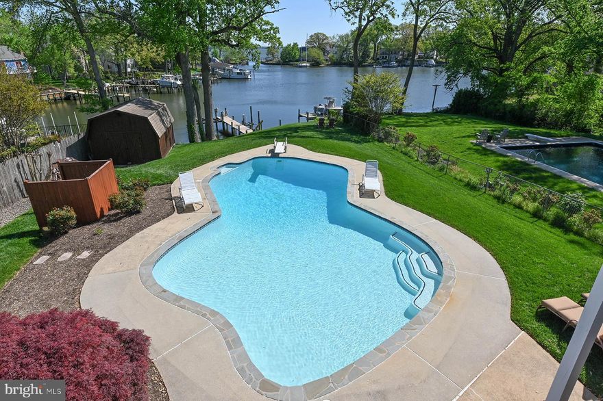 Welcome to 857 Spriggs Court, a charming waterfront home perfectly positioned along Spriggs Pond with wide-open views out to the Magothy River. This property is a rare combination of characteristics: a gentle yet elevated slope to the water, protected deep-water pier with immediate access to the river and Chesapeake Bay, and the jewel in the crown is the waterside pool that gets sun all day long.  Gather with friends on the pool deck, enjoy a break from the heat under shade on the patio, or dine al fresco on the spacious upper deck — all just steps from your private pier. The pier offers a 12,500 lb boat lift and a jet ski lift. Inside, the open-concept main level is flooded with natural light and framed by sweeping water views. The seamless flow in the great room creates the perfect setting for everyday living, dining, and entertaining. The dining area features sliding glass doors that open to the large deck, and extensive built-ins featuring glass-fronted cabinets for display. The kitchen island is the perfect location for a chef who likes to be a part of the action with space for friends at the counter and connection to the other entertaining spaces both indoor and outdoor. The custom wood cabinetry is beautiful and offers ample storage, while the hardwood floors give a warmth to the whole great room. The primary suite is a peaceful retreat, complete with direct deck access, a private ensuite bathroom, and a spacious closet. The hardwood floors continue into the primary bedroom and one of the bedrooms. Two additional bedrooms and full bath complete this level. Downstairs, the walk-out lower level offers a spacious family room with a gas fireplace, direct access to the waterside patio, a full bathroom, and a separate laundry room. There's also a flexible bonus room — ideal for a home office, guest space, or workout room. The utility room offers some additional storage as does the workshop. Located in a coveted “blue ribbon” school district and just minutes from shopping, dining, and major commuter routes, this home offers an incredible waterfront lifestyle at an attractive price. Don’t miss your chance to own a private waterfront oasis with a pier on a protected cove and a waterside pool. An added benefit is watching the ospreys, herons and bald eagles dive for fish…you may even catch dinner from your pier!