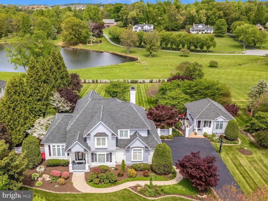 This is truly a remarkable one-of-a-kind home, situated on a magnificently landscaped 1.08  lot overlooking a lake in the The Greens, a small community of upscale homes on estate lots, one of Frederick's most sought-after neighborhoods. With over 6700 square feet of impressively finished living space, this spectacular home is a superb blending of luxury, comfort, style, and livability. - ideal for large or small gatherings of family and friends. This lovely home, which has been almost entirely and meticulously updated over the past several years, only enhancing the features of the original home, must be experienced to be fully appreciated. The main house contains an impressive two-story foyer entrance, first-floor office, chef’s kitchen with custom cabinetry and oversized island highlighted with Calcutta Quartzite Counter Surfaces, 4 bedrooms, 4.5 baths,  gleaming hardwood floors, fully finished basement, two fireplaces and a 3 car attached garage. The family room accesses the rear deck offering spectacular panoramic views of the lake and vast horizon. The rear yards landscaped is picturesque with extensive, elaborate hardscaped patios, walkways, seating areas, and a tranquil Koi Pond with a rippling waterfall. Off the kitchen is a cozy, shaded screened porch with an outdoor grilling station. The separate 2- story guest house is equally lovely with an extra bedroom, a fifth full bath, a kitchenette, and a private deck overlooking the lake. The finished lower level features a home wellness spa/gym including an 8-person sauna. Available for showings by appointment