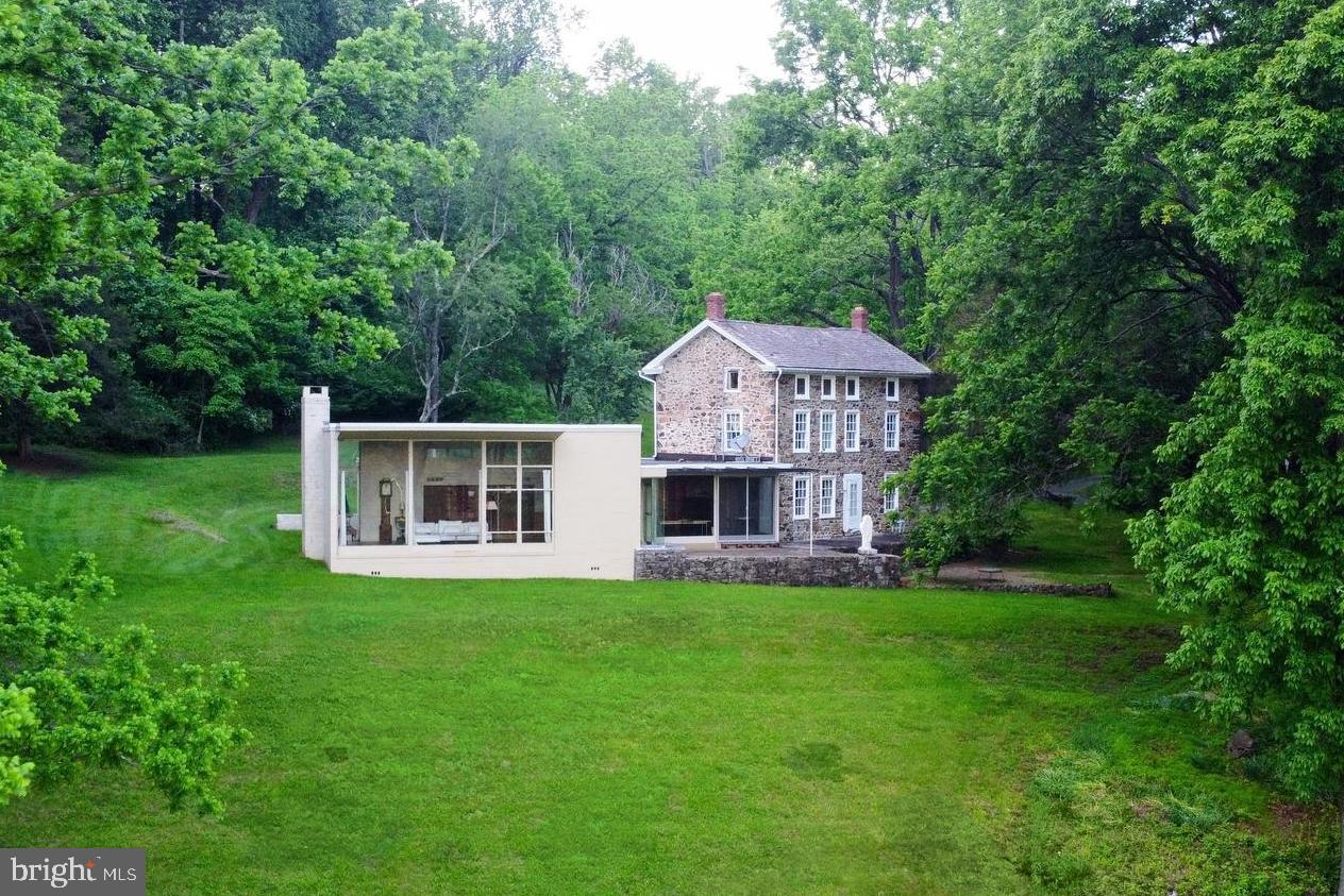 Hidden deep in the heart of Charlestown Township lies one of the most extraordinary properties in the region, protected beauty hidden behind over 80 acres of farmland. Now for the first time being offered as an independent listing, this 39.8-acre parcel includes the historic main residence, a barn, and a studio structure, all tucked deep in the heart of this impressive property with panoramic views of the rolling hills. This is not just a rare property; it’s a sanctuary, fully shielded from the outside world, yet less than 10 minutes to Malvern and Phoenixville, 15 minutes to Valley Forge, and within easy reach of Philadelphia. The property overlooks panoramic views of conserved land, much of it safeguarded by the current owner, ensuring the uninterrupted, soul-stirring views will remain for generations. The original 1860s stone farmhouse was transformed in the mid-1940s by Oscar Stonorov, a pioneering modernist credited for helping to bring European modernism to American soil. His vision is alive in every line of the home, blurring the boundaries between structure and landscape, as floor-to-ceiling windows frame a protected, unchanging panorama of rolling hills and wooded valleys. The Stonorov addition is a living work of art. Anchored by a Georgia marble wall that extends to the exterior, the space features Wharton Esherick handles, and one of the first known instances of glass-on-glass corner windows in American residential architecture. Opposite the Georgia Marble wall is an incredible piece of local art history, the mural study for the painting Philadelphia Panorama. Lucius Crowell was the original owner of this home and before his painting adorned the walls of Hopkinson House in Washington Square, he created the study on this very wall. With farm status tax benefits and deep cultural and environmental roots, this property is as versatile as it is awe-inspiring. Seamlessly blending seclusion with accessibility the property is minutes from major hubs for business, leisure and education. Located in the award-winning Great Valley School District and near some of our areas most elite private institutions such as Montgomery School (Pre-K–8), Villa Maria Academy, Malvern Prep, Kimberton Waldorf, Hill School and Episcopal Academy, finding a school that matches this property's prestige is easy. Opportunities like this do not come twice. This is land you don’t just own, you steward it. A home you don’t just live in, you inherit its story. And a setting that doesn’t just take your breath away, it keeps it. Any sale of an individual parcel is contingent on the coordinated sale of the additional parcels and the finalization of shared access agreements if sold separately. Not all land shown in photos is part of this individual parcel.