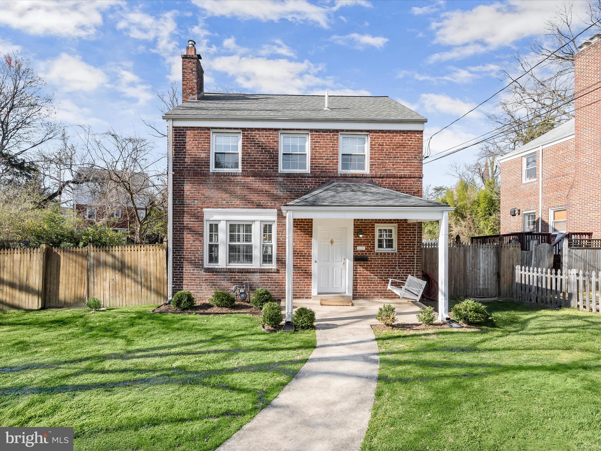 Brimming with character and modern updates, this charming brick home blends timeless appeal with contemporary comforts. A fully fenced yard with a front gate welcomes you to the idyllic covered front porch, complete with a classic porch swing—perfect for relaxing and enjoying the surroundings.
Inside, bright and inviting spaces are enhanced by a neutral color palette, elegant moldings, and updated fixtures. Hardwood and luxury vinyl plank flooring extend throughout, adding warmth and durability. Step into the foyer, where an arched doorway leads to the living room, featuring crown molding, interior shutters, and a cozy fireplace. The seamless connection between the living room and kitchen enhances the home's flow, making it ideal for everyday living and entertaining. The kitchen is both stylish and functional, boasting crisp white cabinetry, an island with a striking marble countertop, and contrasting black granite on the surrounding counters. A marble tile backsplash and stainless steel appliances complete the modern aesthetic. From here, step out to the backyard for easy indoor-outdoor living. Adjacent to the kitchen, the dining room offers a refined touch with crown molding and chair railing. A convenient powder room concludes the main level. Upstairs, three bedrooms, including a spacious primary, are filled with natural light and showcase beautiful hardwood flooring. The full bath is designed for relaxation, featuring a jetted soaking tub and modern fixtures. The lower level expands the living space with a comfortable family room highlighted by luxury vinyl plank flooring and walk-up access to the backyard. A full bath on this level adds versatility, while storage closets and a utility room with laundry provide practicality. The backyard is a true retreat, offering thoughtfully designed spaces for play, picnics, and fireside gatherings—all surrounded by fencing and blooming trees. A stylish storage shed provides both form and function, with a workbench inside and pull-down stairs leading to an upper-level storage area, making it a perfect space for hobbies or additional organization.
Practical updates include a roof that is just six years old, providing peace of mind for years to come. Additionally, this home offers an incredible financial advantage with a VA assumable mortgage at a low 2.7% interest rate—an opportunity not to be missed. Ideally located, this home is just moments from Sligo Creek Park, offering endless outdoor recreation. Enjoy walking distance to downtown Takoma Park, three major bus lines, the Takoma Park Metro, and the upcoming Metro Purple Line stop just up New Hampshire Avenue. With Washington, D.C., just minutes away, this home offers the perfect balance of charm, convenience, and accessibility. Please note: photos depicting furniture have utilized virtual staging.