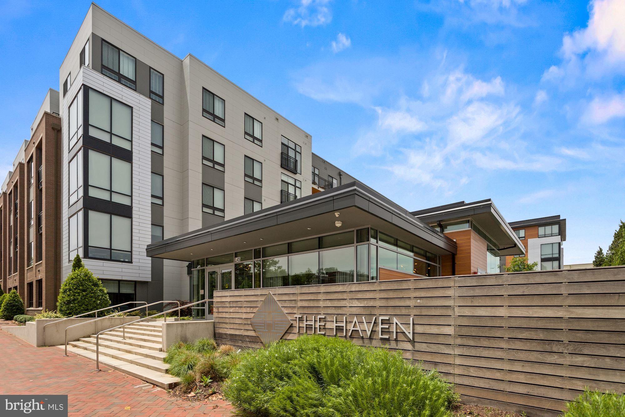 Resort-style living with unmatched amenities just minutes from D.C. and Northern Virginia. This beautifully upgraded residence is ideally situated steps from the community’s premier amenities. Thoughtful custom touches include recessed lighting, designer paint, and ceiling fans in both the bedroom and den.
The stylish open-concept layout features a gourmet kitchen with stainless steel appliances, quartz countertops, an oversized island, and custom cabinetry. The living area includes a cozy fireplace, Juliet balcony, and hardwood flooring throughout. The spacious primary suite offers a large walk-in closet and a spa-inspired bathroom with a glass-enclosed shower, dual vanity, upgraded mirrors, and linen closet.
The second bathroom includes a soaking tub, vanity with extra storage, and designer wallpaper. The generous den with its own closet can serve as a second bedroom or office. The unit also includes two deeded, high-clearance parking spaces conveniently located near the entrance.
Residents enjoy access to The Haven’s impressive amenities: an outdoor pool, a state-of-the-art fitness center with yoga studio, a resident lounge with billiards, pet spa, bike storage, and more. A friendly 24-hour concierge is always available to assist with your needs.