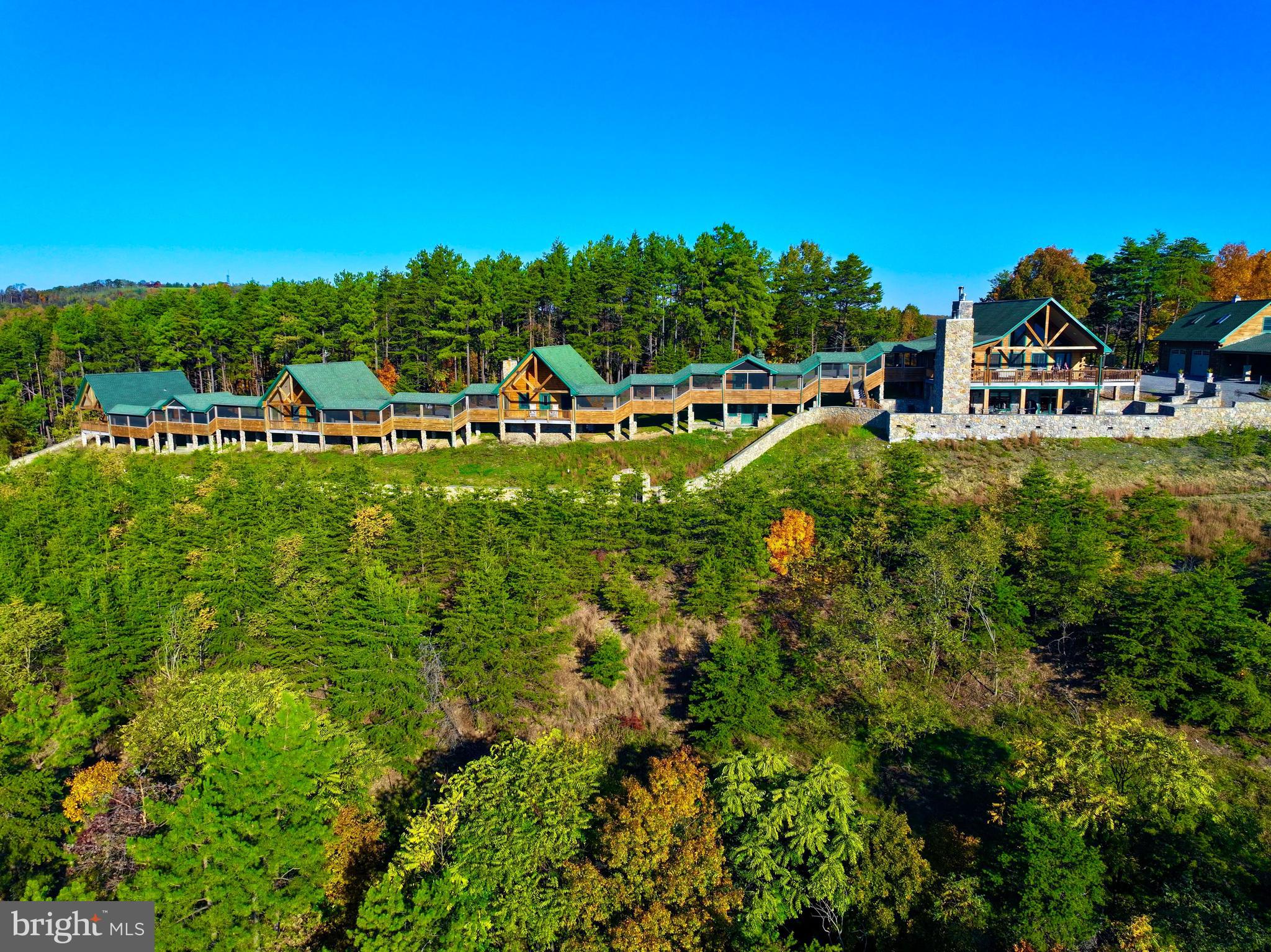 It's all about the views. Have you ever seen a house on top of a mountain and said I bet they have an amazing view? You will find just that and a whole lot more at 570 Bluffs Potomac Road. Would you love to own a place that the entire family could visit and have a place to sleep? Do you love to entertain large crowds and celebrate the holidays in style? This property offers just about everything you can think of. This 25+/- acres is secluded and in a gated community. From the main home which features multiple levels, to 3 additional cabins that are accessible by a screened in walkway and have their own kitchens, plus 2 additional bunkhouses you have plenty of room for all your guests and entertaining needs. This property boasts several highlights from outdoor fireplaces, a privacy wall around the house, a detached oversized garage with a large bonus room above it, a custom pool table, an extra well, a sound system that filters to both the outside and inside the main cabin, the list goes on and on. This is a home you have to see to believe. There is a generator that runs the main house and garage when the power goes out and the property has been well maintained. This place gives you a resort feel in the privacy of your own back yard. The oversized porches are a perfect place to watch the sunrises and sunsets cascade over the WV mountains. Less than 3 hours from Baltimore and Washinton DC this place is truly one of a kind. The HOA restricts short term rentals of any kind and any commercial usage of the property. Call today to schedule your private showing. You'll be glad you did.