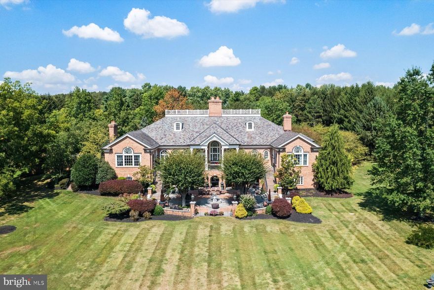 66 ACRES- Incredible opportunity with two adjoining parcels.TWIN PONDS  is a superior combination of exquisite architectural designs by Spence Kass & Associates and old-world craftsmanship using only the finest materials throughout. It represents a combination of specially selected items discovered and outsourced from the owner’s travels around the world and a collaboration with prestigious designers.
The grounds are equally as majestic as the sprawling country estate thoughtfully sited high and center with captivating views of the rear Twin Ponds, swimming swans and 60+ acre terra backdrop that sits directly behind. The iron gated approach is secure, and tree lined. The approach to the front entry is grand with a royal circular drive around large fountain. The heritage trees, ponds and scenic landscaped gardens all feature irrigation and professional landscape lighting creating an enchanting estate wonderland like no other.
This Georgian inspired masterpiece strikes a harmonious balance between formality and ease of play. The main level floor features an elegant entry marbled foyer with regency style Baccarat chandeliers and sconces. The Great room features English country charm with buoyant blues, grand chimney piece from France, detailed ceilings and tall custom built in cabinetry. The Dining room resembles the Edwardian era with artist hand painted mural of the property vistas commissioned of the property landscape. The heart of the home is the custom Joanne Hudson kitchen with William Oh cabinetry, dual working islands, very top-of-the-line appliances including 10’ La Cornue French range, two Meile dishwashers, oversized Sub Zero French door Refrigerator/Freezer and refrigeration drawers. The kitchen features a dramatic hand painted stained glass skylight above and numerous oversized French doors to outdoor portico. Grandiose unfolds as you move through the main floor – it’s the levity in all the luxury. The living rm and main bedroom suites are warm with richly layered textures, museum quality European chimney pieces and floor to ceiling windows. They infuse English high style with a generous dose of French. The marble BR spas all feature Sherle Wagner luxury fixtures, Italian veined marble and regency crystal light fixtures. The handsome library boasts hand crafted detailed millwork and leathered ceilings – An ideal spot to sip whiskey and relax.
Enter the lower level by elevator or stairs for more casual family entertainment. Special features include a spacious family gathering room with wall of French doors covered bluestone patios, large wet bar and kitchenette with all the bells and whistles, handsome Billiards room, Pizza Kitchen which would rival ANY food network show with its equipmnt, space and incredible details, Spa with large marble tub, sauna, etc. Around the corner is an award-winning wine cellar with custom iron gate doors handcrafted in France and wine tasting area to savoir the labor of grapes.  In addition are an abundance of large storage closets and several meticulous mechanic’s room. Attached to main level and entry into mudroom is an oversized four-car heated garage with motor courtyard outside. Other features include full house generator, radiant floor heat on entire main level, sophisticated Lutron electric system and generator for the entire house and Geothermal system as well. It’s obvious that NO expense was spared during the construction and maintenance of this one-of-a-kind property. Outbuildings are plentiful on an estate of this size and magnitude. You’ll see a show stopping, refurbished and modernized 1853 Bank Barn featuring two stories. The fieldstone is impeccable, and the interior is modern. There’s a professional size sport court and 4000 square foot maintenance workshop with garages to house all of the property equipment such as tractors, golf carts and gators, etc. There is no other estate property in Pennsylvania that Rivals Twin Ponds. 30 min to center city/20 mi