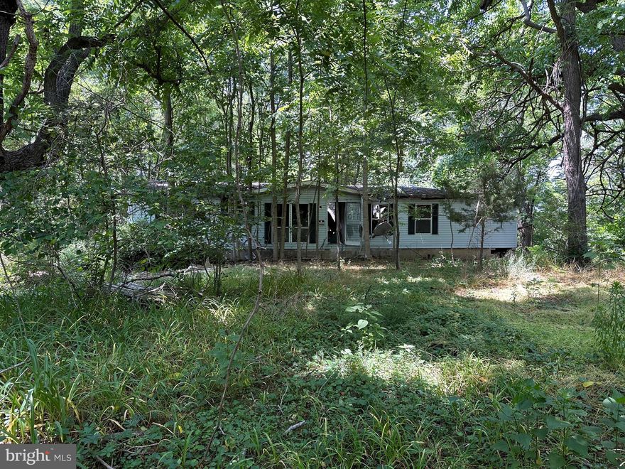 This one acre lot is wooded with a 1991 double wide that sustained fire damage from a few years back. As per the County, it is past the 2 year replacement status. Options are rehab or to remove the structure. There is an existing well & septic from 1991 (documents in hand). The well is 120 feet deep and septic is approved for 3 bedrooms. Conditions of well & septic are unknown. Electric service is present and ready to build your new home. There is a deeded 50 ft right of way running past 11335 Needam Road to access the lot (see plat). Please do not walk the property without the Listing agent. Contact planing and zoning or surveyor to confirm/verify lot lines. Update: We are currently working with a contractor to locate the well & septic and test to see if both are still viable. Seller may get a new survey.
