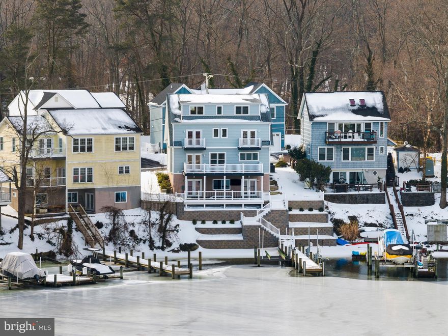 Perched along the waterfront of Cool Spring Cove, this thoughtfully enhanced residence delivers a seamless blend of comfort, recreation, and effortless coastal living, where extensive upgrades elevate both daily enjoyment and entertaining. The outdoor environment has been carefully curated to maximize time on and around the water, with redesigned hardscaping, custom lighting, lush landscaping, and irrigation creating a polished yet low-maintenance setting. Expansive multi-level decking invites gatherings of every scale, featuring a fully rebuilt lower deck with a private hot tub retreat and sleek, unobstructed railings that preserve water views, while the upper deck’s remote-controlled awning allows for shaded relaxation during warm summer afternoons.

The private pier system transforms the property into a true boating and waterfront lifestyle hub, featuring a 12,000-lb boat lift capable of accommodating a substantial vessel, dual jet ski lifts for spontaneous adventures, upgraded electrical service, and convenient water access via an integrated ladder. Thoughtful additions such as docking bumpers, cleats for visiting boaters, and live well and crabbing accommodations create the ideal setting for sunset cruises, weekend water sports, and enjoying the Chesapeake’s renowned crabbing traditions. 

Inside, extensive interior enhancements enrich everyday living while providing exceptional spaces for hosting. The main level layout flows seamlessly from the dining area, living room with fireplace and the spectacular white kitchen with large island and fabulous views. The finished lower level is designed as an entertainment destination, showcasing a custom bar with refrigeration, keg chiller, dishwasher, and ice maker, along with a theater room, gathering lounge, and spa-inspired full bath that offers guests and residents alike a resort-style experience. 

The primary suite boasts exceptional water views and provides a luxurious escape with cherry hardwood flooring, custom closet, conveniently located laundry room and a stunning spa-like bath with free-standing soaking tub overlooking the water. 2 additional bedrooms on this level and an expansive additional upper level with full bath, views and plenty of space; provides ample options for accommodating family and friends. 

Together, these extensive improvements create a turnkey waterfront sanctuary designed to support an active boating lifestyle, memorable entertaining, and relaxed everyday living. Welcome Home!