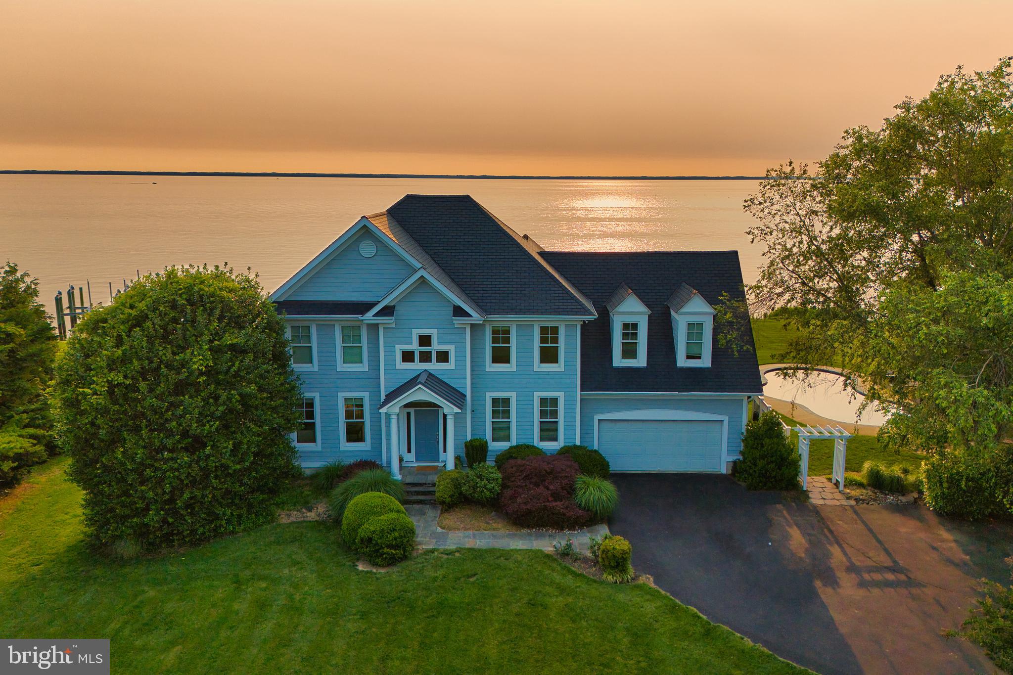 Welcome to a Chesapeake Bay retreat where spectacular views and unparalleled waterfront living await. Perfectly positioned on a serene cul-de-sac, this elegantly appointed home offers breathtaking vistas of the iconic Bay Bridge, majestic lighthouses and sunsets that will leave you speechless.
Upon entering into the 2 story foyer, the formal living room and bonus room welcome you and provide ample space for unwinding or hosting guests. The thoughtfully designed interior boasts 5 spacious bedrooms and 4.5 luxurious baths, including an upper-level primary suite with a cozy sitting room and yacht-inspired bathroom. The finished lower level with full bath and bedroom provides additional space including a wet bar and refrigerator accommodating friends and family of all ages. Natural light floods every room and frames the serene water views at every turn, accentuating the open-concept kitchen, dining area, and family room that flow seamlessly into the outdoor, covered living spaces.
Three sets of oversized French doors lead out to the stunning waterside patios, a saltwater heated pool, a cabaña, and a pool bath, creating the perfect environment for relaxing or entertaining as you take in the beauty of the bay. The private dock with 2 boat lifts (12,500 & 30,000 lb) offers opportunities for fishing, crabbing, and boating, completing the ultimate waterfront lifestyle. This home is more than a residence—it’s a masterpiece of design and nature, crafted to immerse you in the soothing rhythm of life on the bay.
Welcome Home!