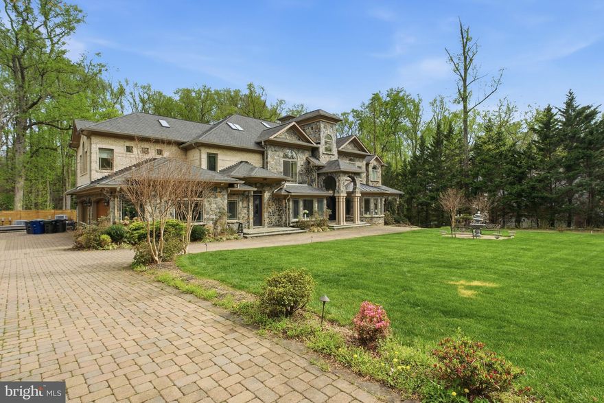 Experience unparalleled scale and sophistication in this 14,800-sq.-ft. masterpiece nestled on a private 1.26-acre sanctuary in Woodside Estates. This 2017-built Colonial features 8 bedrooms and 12 bathrooms across four finished levels, highlighted by a breathtaking foyer with a curved double staircase. Rare amenities include a climate-controlled indoor swimming pool for year-round luxury, a dedicated state-of-the-art home theater, six heated car garages, a 16000-watt Generac generator, and a dual-kitchen system featuring a gourmet primary kitchen plus a full catering galley. The expansive floor plan offers a main-level guest suite, five gas fireplaces, and a walk-out lower level complete with a professional wet bar and fitness suite. Outside, enjoy a tranquil creek-side setting and stone patio, all just minutes from the world-class shopping of Tysons Corner and an easy D.C. commute. The ultimate blend of grand architecture and private resort living.
