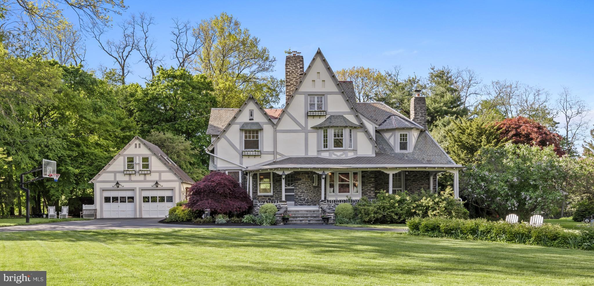 Walk to Wayne from this historic, beautifully maintained Tudor home situated on a sprawling corner lot. The owners of this 1892 property have taken great care to preserve its original charm and detailing while updating it with the modern features and conveniences that today’s buyers crave. A circular driveway brings you to an elegant, expansive stone front porch that provides the perfect place to relax and unwind. Inside, a gracious foyer with wood-burning fireplace connects to a sunny dining room with original moldings, built-in cabinetry and scenic front yard views. The dining room leads to a gourmet kitchen with numerous high-end amenities, including granite countertops, a six-burner Wolf gas range, a Thermador warming drawer and a custom paneled refrigerator. The kitchen spills into a grand family room—part of a three-story, open-concept addition completed by the current owners. From custom built-ins to the convenient slider access to the rear flagstone terrace and private, tree-lined backyard, this room contains all the elements for effortless living and entertaining. Just off the family room sits a large, stately study/den/entertainment room with bay window, mahogany accents and open stairway leading to a large finished basement with full bathroom. The 2 story addition; family room, entertainment room and primary suite have radiant heat floors. A cozy living room with wood-burning fireplace, two powder rooms and a secondary stairway off the kitchen complete this fabulous first floor. The private, well-designed primary suite is located on its own level and features a walk-in closet, en suite full bath and abundant natural light. The next floor includes three well-sized bedrooms—each with ample closet space—plus a spacious laundry room with utility sink. Tucked away on the home’s uppermost level you’ll find another bedroom and full bath, along with an unfinished attic that could be converted to additional living space. The expansive one-acre lot—set far back from the street—provides plenty of space to play, and the detached, two-car garage houses an upper-level studio that’s perfect for a home office or gym! Located on one of the most beautiful streets in Wayne, this Main Line masterpiece is within walking distance to parks, a skating and fishing pond, public transit, local schools and premier shopping and dining. Award-winning Radnor Township School District.