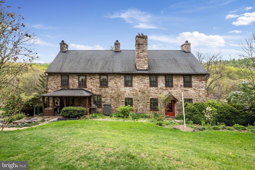 Situated at the foot of North Mountain is this historic federal farmhouse circa 1790. This home is adorned with stone and log, two 64' front porches of tongue and groove mahogany with wainscoting ceilings (restored 2023), six fireplaces throughout (2 used regularly), original federal door and trim details, heart pine floors and exceptional stonework. There have been many upgrades over the years for contemporary living to include electrical upgrades, architectural shingles on main house in 2010, new gutters in 2019, new wood stove in 2016, new heat pump in 2017 (regularly serviced), gas logs in living room fireplace, three storm doors, granite kitchen counters, mostly copper plumbing, covered porch off of the kitchen, and septic line replaced  from house to tank in 2018. You will find beautiful exposed beams, built-ins, lovely mantels, windows and trim, 2 stair cases, functional barns, and beautiful exterior grounds with views and privacy. The back of the property adjoins a 10,000+ Acre farm. This 7+ acre parcel is showcased with ornamental and indigenous trees, beautiful gardens with lovely flowers and plants highlighting each season . The plethora of trees, plants and flowers you'll discover include fruit trees of apple and peaches, walnut trees, pawpaw trees, hickory trees, red buds, day lilies, lilacs, forsythias, tulips, daffodils, bluebells, hellebores, herbs and more - all bringing in over a 100 species of birds and butterflies. There's still so much more to explore and discover as you tour this property; a stone patio, walk way and retaining wall, 2 large barns, a gorgeous stream, the remains of a spring house and old stone foundation,  boulders that give character to this land and  that have created a natural cave. Both barns have metal roofs. The first barn is 20x40, it has electricity and loads of storage. The second barn can serve as a run in shed, it has a loft, a great space for potting and has a partial 1/2-1 acre fenced area. You'll enjoy the drive to Bloomery taking in lovely farms with mountain views and will appreciate that it is only a 20 minute drive from Winchester.