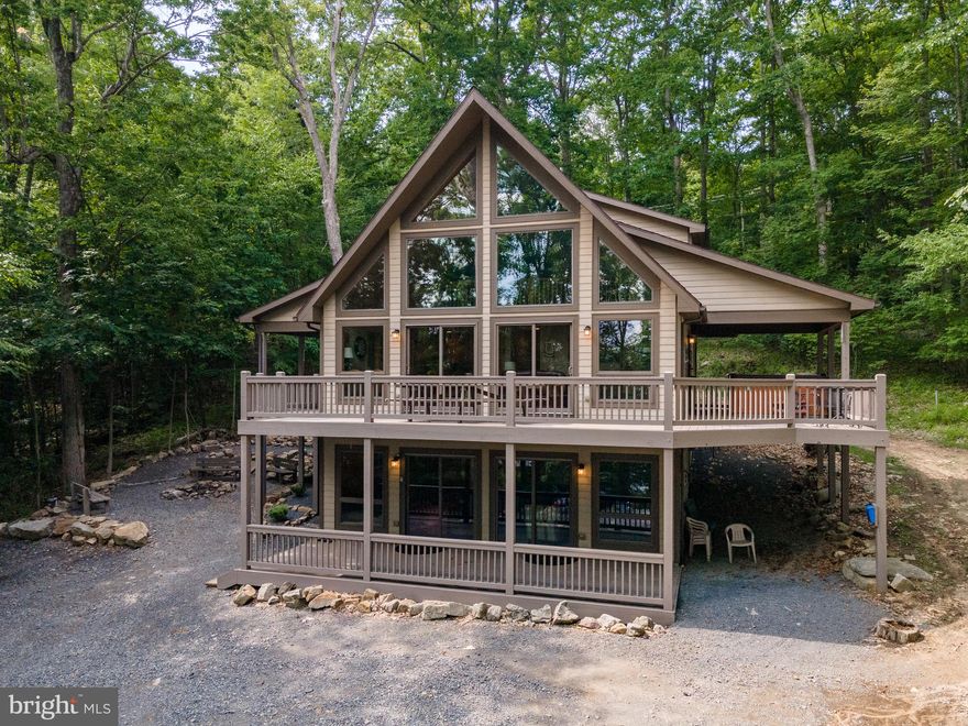 Charming Cedar Chalet at Deep Creek Lake - Conveniently located just off Glendale Rd, this 5Bed 4bath Lake Home features an enormous wrap around deck, vaulted ceilings, two stacked stone fireplaces, lower level game room, and tons of glass to bring in the panoramic views of Deep Creek Lake! Your Primary Suite makes up the entire upper level, with additional space on the adjoining loft and walk-out balcony. Situated on almost half an acre of wooded land, just minutes from state parks, local restaurants, and Wisp Resort. Enjoy the cool evenings around your outdoor firepit, or soak up the mountain air from your private covered hot tub. An established rental, “Crabby Badger”, would make an excellent vacation rental or private mountain getaway… Call today for details!