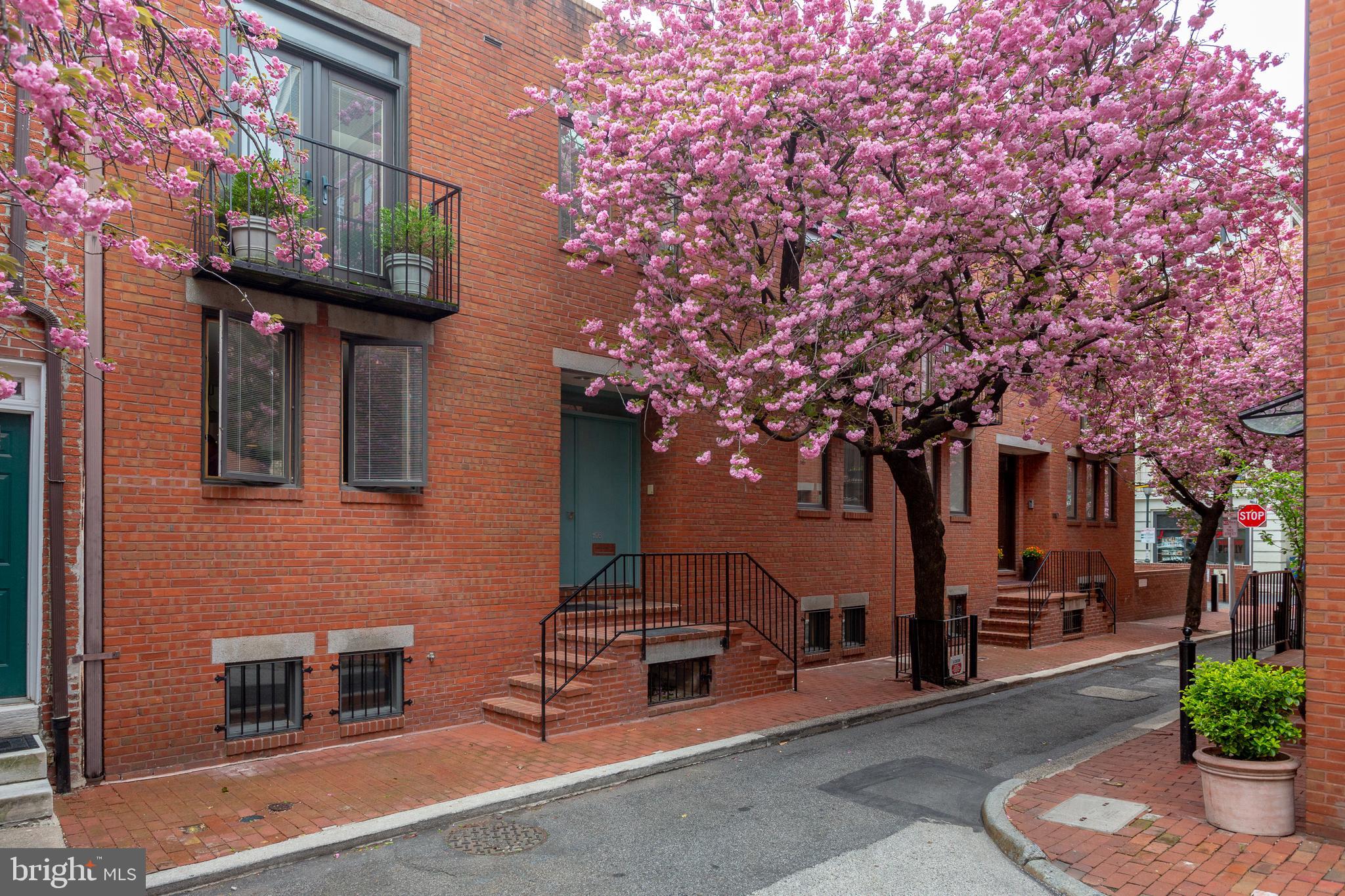 Stunning for its extraordinary 36-foot width and outstanding natural light, this Marvin Verman-designed townhouse is the definition of open, gracious living space. Verman, a student of Louis Kahn, created this residence in 1979 on a picturesque half street hidden from the hubbub of the city. Lined in cherry trees that put on a show each spring, this home s setting provides beautiful views and is convenient to Philadelphia s top arts venues, restaurants and shopping. The home s brick construction and fa ade fit squarely with the block s more traditional homes, but step inside and the serene spaces created by interior designer Michael Murtha elevate your living experience like no antique home can. At only two stories high, this property is wide and deep with 2,520 square feet, two Juliette balconies and a walled, 36-foot-wide garden space at the rear of the house. Picture windows, casement and clerestory windows along with 10-foot ceilings create light-filled spaces. Vast expanses of wall space await your art collection. Entertain with ease the living, dining and kitchen areas accommodate a crowd and the poured terrazzo flooring holds up to the heaviest of foot traffic. Top-grade materials are used throughout this home. The timeless kitchen is outfitted with stainless steel Thermador, Sub-Zero, Miele and Bosch appliances and dual sinks with views down scenic Sartain Street. Custom lighting, metal work, cabinetry and wood paneling add quality and warmth throughout. Both the living and dining areas have views of the rear garden via picture windows, and the step-down living room is warmed up with wood wall panels and a gas fireplace with slate surround. An office and powder room complete the first floor. Private quarters are on the second floor. With vaulted or angled ceilings and clerestory windows, the play of light in the rooms is delightful. The main bedroom suite is as spacious as that of a suburban home with roomy sleeping quarters with sitting area; a bath featuring dual vanities, an oversized walk-through shower with body sprays and bench, and a separate toilet room; and a well-designed walk-in closet with a variety of built-ins, capped off by a laundry area with full-sized washer, dryer and utility sink. Across a wide central hall are two guest bedrooms, each with a Juliette balcony, and a shared bath offering a jetted tub with rainfall showerhead and regular showerhead. There are so many delights and surprises built into this home by the architect and interior designer. To appreciate these features along with its calm energy and natural light requires an in-person visit. Schedule your tour of 1108 Manning Street today.