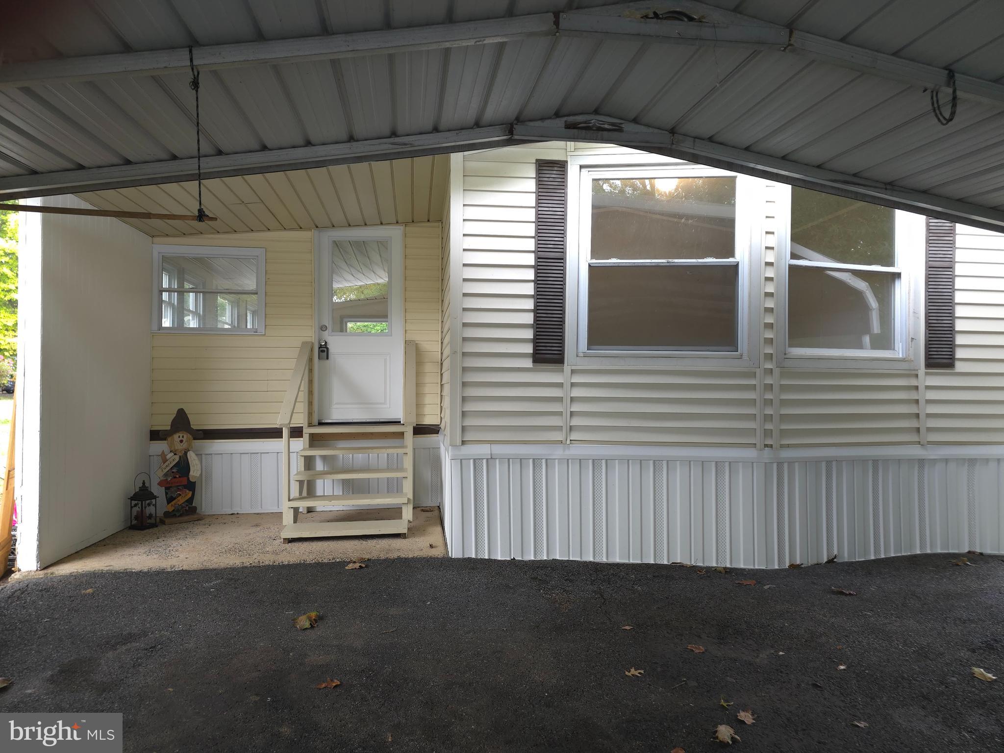 As you drive by the beautiful corner lot, you will notice mature trees, rose bushes, and a butterfly bush, etc. Next pull into the driveway and get out under the carport. Walk up to the mobile and go into a 3 season room and then go into the mobile to the living room. Turn left to a full bath and a bedroom. Turn right into the living room and then go into the kitchen with a new butcher block island to sit and eat, next is the laundry room, and go through to the primary suite. New flooring throughout and many upgrades. Schedule your showing quickly, this won't last long. Must be park approved. One owner is a Pa licensed Realtor.