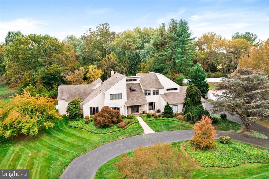 A rare offering has come to the market!
Situated on a beautiful street in a coveted neighborhood in Yardley, this contemporary has it all. Set back on an acre lot of professionally planted and maintained trees and shrubbery, this property offers a breathtakingly beautiful Shangri-la of specimen trees, wooly lamb's ears, and even a fig tree. From the outside, the covered entrance is welcoming and elegant, and inside, the volume ceiling, skylight, and hardwood floor in the gracious entry only hints at the sophisticated modifications and upgrades you will find in this home. A masterfully crafted, eat-in kitchen has everything a chef could want, from the gorgeous cabinetry, to the top of the line appliances and custom tile work, with plenty of room to chat with the cook (and each other) from the granite island. Custom floor and dining area blend together beautifully, and the sliding glass doors create a wall of glass, open to the paved terrace. What a perfect melding of inside and out! Open to the family room, this combination of spaces offers a feeling of congeniality and ease of living found throughout the house.  A wood burning fireplace adds warmth and charm, and glass doors to the terrace make access to the garden inviting and simple. Returning to the entry, another wing beckons.  A convenient study leads to a masterful addition of a lavish main bedroom, creating a private suite. The generous sized bedroom has beautiful built-ins and a lovely window wall plus a gas fireplace The closet is a work of art designed by the current homeowner. Recessed lighting, shelves that go on forever, drawers, a center island, and hanging racks galore, you will always have “room for one more "!  Accessible, beautifully tiled shower, heated floor and custom fittings, walls and vanities add to the already off-the-charts luxury.  You will never need to go upstairs, but if you choose to, there are 4 more bedrooms, including the original main bedroom, so if you want to be on the second floor, you most certainly can. This main bedroom has a cathedral ceiling and fan, and sumptuous bath complete with beautiful custom wood built-ins and granite counters. Stunning tile work is evident in the shower, with a touch of whimsy in the tiling reminiscent of sea stones, and little touches like a built in shelf, 2 shower heads, and recessed soap dish. A private balcony overlooking the gardens makes this second level bedroom another special treat. There are 3 additional bedrooms and a hall bath. Add to all of this a three car, over-sized side entry garage with new EV charger, plus a full basement and full  house generator. Truly a work of art, this property offers everything you want in luxury living, including excellent schools, easy access to transportation, shopping, Princeton and Philadelphia.
Preferred settlement date not before March 2026.
