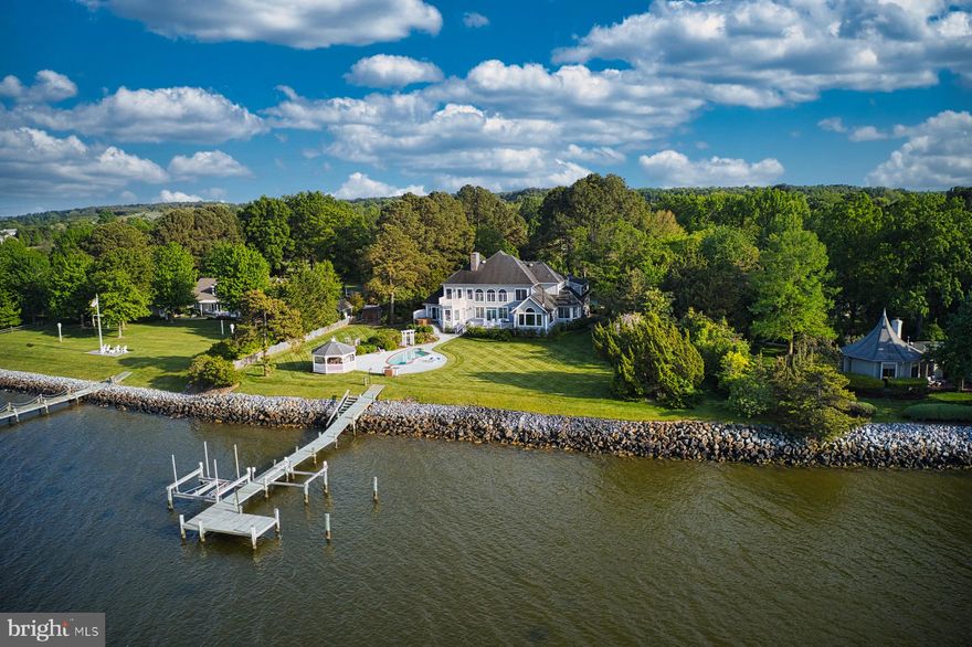 This property on a quiet three house cul-de-sac in the desirable Martingham neighborhood offers both close proximity to St. Michaels and breathtaking, panoramic and endless vistas of Porters Creek, Miles River, Wye River and the Eastern Bay by day and the sparkling lights of Kent Island Bridge at night. Sited high above a rip-rapped shoreline, the house’s rear wall is infilled with long windows and doors for maximum water views from most of the main rooms.

Enjoy the outdoors from elevated decks on the main floor living room and primary bedroom and the guest ensuite on the second floor, take a dip in the waterside pool, enjoy the hot tub or launch your boat from the either of the pier’s two boatlifts from an afternoon on the water. Relax afterwards in the spacious screened gazebo perched at the top of the shoreline for endless views.

The traditional style two-story house with abundant daylight from numerous windows, offers one-level living on the main floor including a sumptuous primary ensuite with a fireplace, living room with fireplace, dining room, study, open plan kitchen-breakfast room-family room, mud room and a three-car garage. Guest rooms and a bonus room are located on the second floor with a second stair to the main floor. One ensuite bedroom could also be a primary suite. The bonus room over the garage offers myriad possibilities including an artist studio, office or playroom. The basement level includes a spa area with a four-person sauna, fully equipped fitness room and storage.  as well as 2 bedrooms for overflow. The floor plan is zoned very well with easy flow among the rooms and the decks for relaxing with family and friends.

Amenities include flower gardens and a raised vegetable garden with shed, sprinkler system, public water and sewer plus a well for unlimited water supply, and broadband internet. No flood insurance is required due to the high elevation above the riprapped shoreline.

Move-in ready for you to enjoy the summer season!