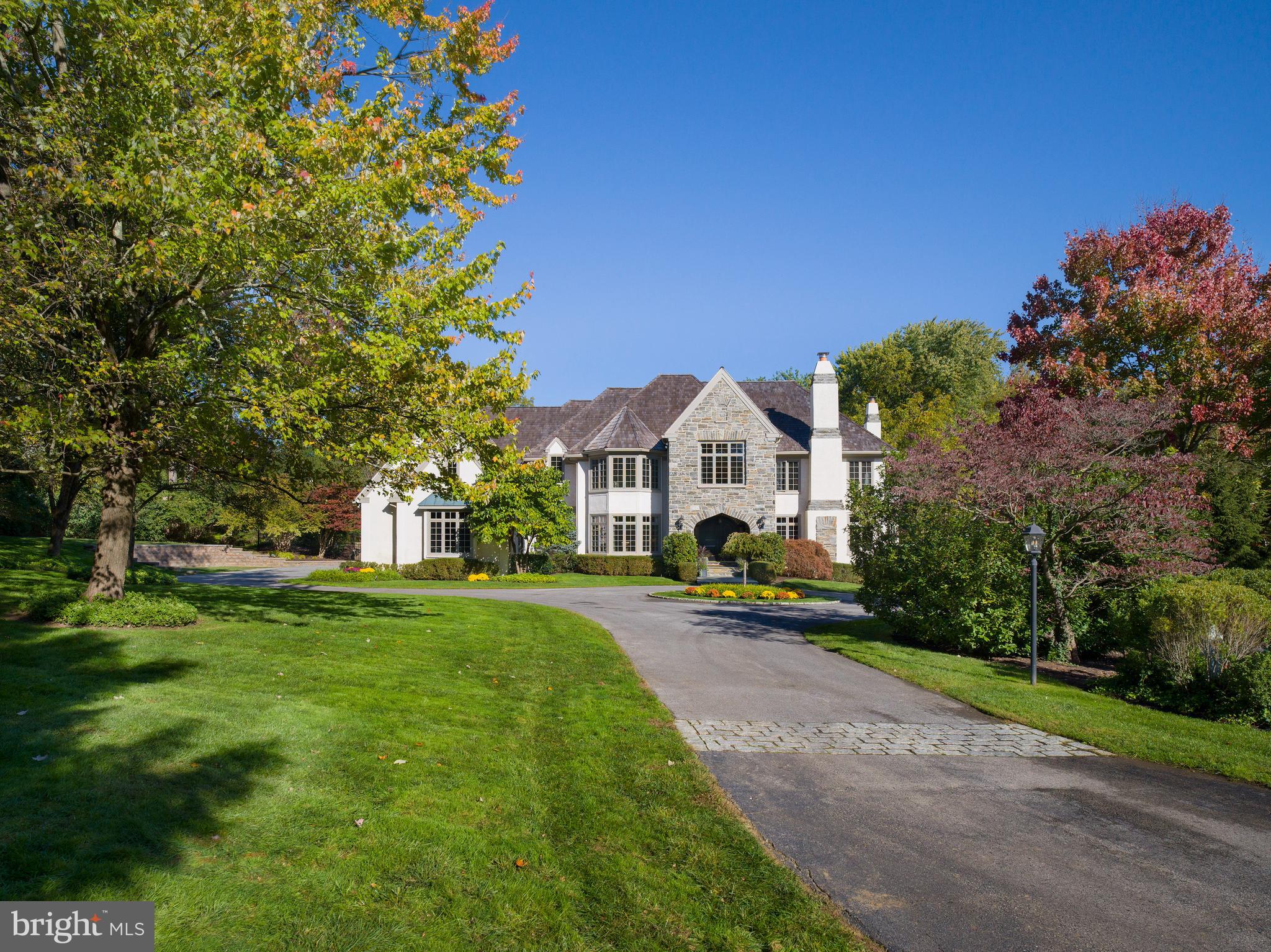 This home was custom-built by renowned Main Line builder CF Holloway, has been masterfully updated to reflect the interior design preferences of today’s luxury home buyers. Nestled on a serene 1.5-acre cul-de-sac lot in North Bryn Mawr, this residence is part of the prestigious Henley on Kyneton development. It combines tranquility and convenience, with easy access to Lower Merion Township’s award-winning schools, elite private schools, and vibrant local amenities.
The home features 6 bedrooms, 6 full baths, and 2 half baths across approximately 8,500 square feet of thoughtfully designed living space. Enter through the custom mahogany double doors into a welcoming vestibule that opens to a dramatic two-story foyer with a curved staircase and oak flooring throughout the main level.
The living room and dining room are beautifully proportioned with large windows, including a triple bay window in the dining room, accentuated by wainscoting and abundant natural light.
The family room boasts a gas fireplace with floor-to-ceiling stone surround, built-in cabinetry, and a custom entertainment cabinet. Double doors lead to a two-story screened porch with vaulted ceilings, skylights, and breathtaking views of the rear preservation space.
The chef’s kitchen is a culinary masterpiece with double-thick countertops and seating, premium appliances from Sub-Zero, Thermador, and Miele, and thoughtful details designed for entertaining and convenience. It features two dishwashers, fridge and freezer drawers, a built-in coffee maker, and a walk-in pantry. An oversized two-story window bathes the space in sunlight, while the adjacent breakfast room features built-in cabinetry and a large window overlooking the rear terrace and pool.
Two flexible spaces enhance the main floor. The home office features floor-to-ceiling wood paneling, a gas fireplace, and access to a large rear deck. The den, with a wall of windows and French doors, opens to the trellised portion of the terrace, which includes an outdoor fireplace.
The first floor is complete with a custom wet bar, two powder rooms, and a mudroom offering a spacious laundry room with countertops for folding and cabinetry for storage, as well as inside access to the 3-car garage.
Upstairs, the primary suite is a private retreat with a spacious bedroom featuring a vaulted ceiling and French doors opening to a porch. A sitting room, makeup vanity, soaking tub, and steam shower with a frameless glass door enhance the luxurious primary bathroom. The suite includes two oversized walk-in closets, one with a center island, abundant hanging space, and built-in storage.
The second floor also features four additional bedrooms, all with walk-in closets and en-suite baths.
The walk-out lower level is an entertainer’s dream, with walls of windows, a home theater, wine cellar, exercise room, bonus room, and a bedroom with full bath.
The rear grounds are a private oasis, featuring estate fencing, a terrace with an outdoor kitchen, and a trellised roof over a portion of the terrace. The swimming pool and spa are surrounded by mature landscaping, with a waterfall flowing into the pool for a resort-like ambiance.
Additionally, most of the roof is only 1 year old, offering peace of mind and long-term durability.
Conveniently located less than a mile from the Villanova and Rosemont train stations, this home offers easy access to Center City Philadelphia, the charming town of Wayne, and the Jersey Shore. With a whole-house generator for added peace of mind, this home is a rare combination of timeless design and modern luxury.