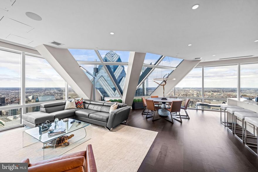 Perched high above Center City on the 56th floor of the iconic Two Liberty Place, this extraordinary penthouse delivers a rare opportunity to own one of Philadelphia’s most breathtaking residences. One of only four homes on this exclusive level, the residence was thoughtfully designed with elevated architectural detail and refined luxury throughout.

Soaring nearly 11 feet high, dramatic convex and concave floor to ceiling windows create a true in the sky experience, framing sweeping panoramic views of both the Schuylkill River and Delaware River. From the primary suite, the neighboring One Liberty Place becomes a striking architectural backdrop unlike anything else in the city. Morning sunrises and evening sunsets paint the skyline in every direction, offering a perspective few will ever experience.

Designed for both comfort and entertaining, the expansive open concept great room is anchored by a statement curved glass wall and gas fireplace, creating a natural separation between the luxurious primary suite and the flexible guest bedroom or private den.

The chef’s kitchen blends sleek European design with high performance function, featuring premium Miele appliances, a Sub-Zero refrigerator, wine cooler, and elegant Italian Snaidero cabinetry.

The primary suite is wrapped in dramatic glass panels and complemented by a custom dressing area and oversized walk in closet. The spa inspired bath is finished in warm grey and white marble and includes a soaking tub, glass enclosed shower, and dual vanities. The spacious second bedroom or den offers its own marble bath and generous closet space.

A marble powder room and separate laundry area are discreetly positioned for everyday convenience.

Residents of Two Liberty Place enjoy a full suite of luxury amenities, including 24 hour doorman and security, valet and self parking with unlimited guest access, private storage, and direct access to the Shops at Liberty Place. The newly renovated 37th floor amenity level, completed in March 2024, features a state of the art fitness center, indoor pool, massage room, yoga studio, sauna, steam room, business center, multiple boardrooms, and an expansive residents lounge with sweeping city views. An additional third floor amenity space offers breakfast through lunch service from 7:30 AM to 3:30 PM exclusively for residents and building employees.

Originally showcased as the developer’s model residence and meticulously maintained, this exceptional penthouse is offered unfurnished, with furnishings negotiable.

Iconic views. Elevated privacy. Unmatched Philadelphia living.