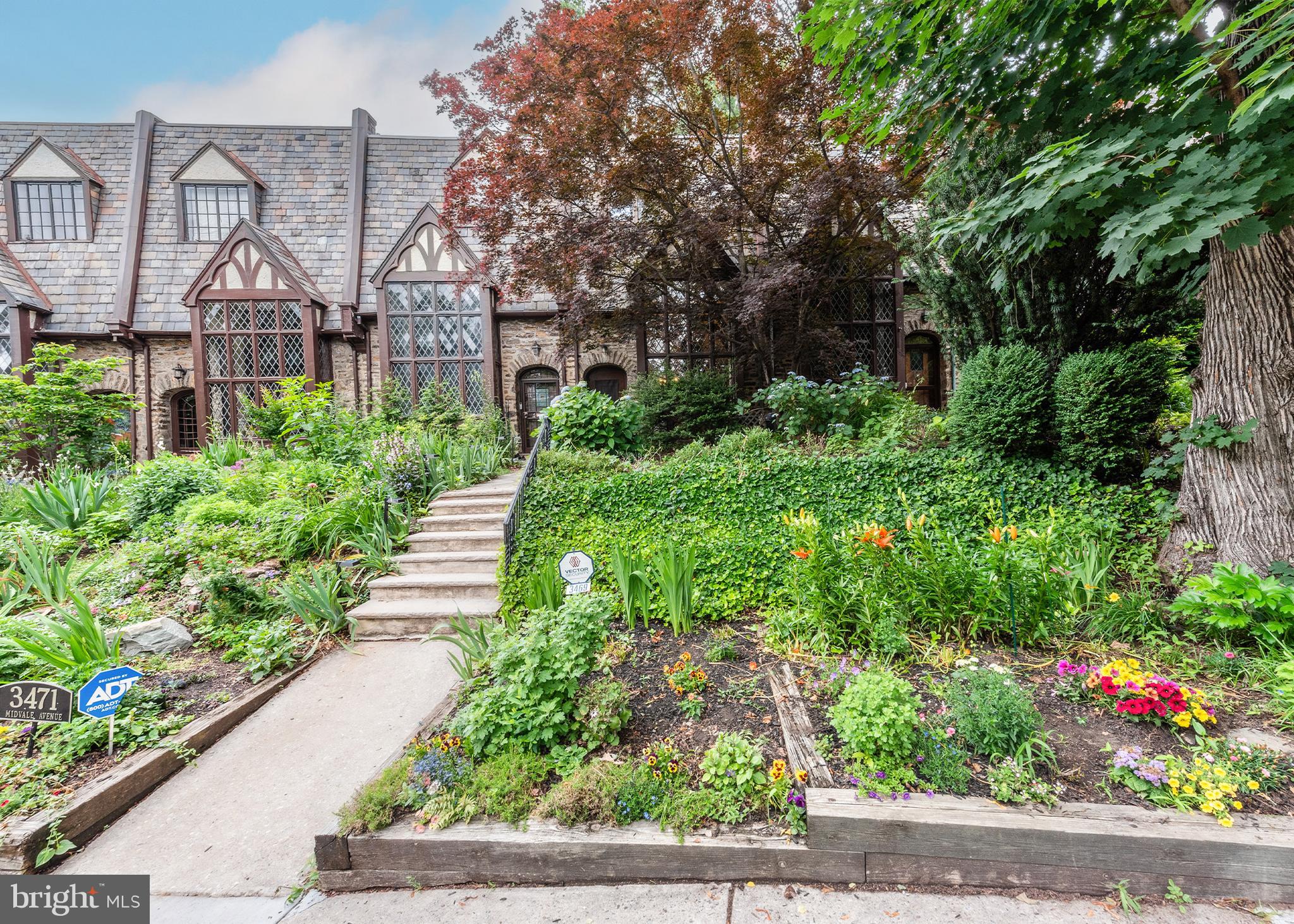 3469 Midvale Avenue is a gorgeous example of the 1930s Tudor East Falls Historic District, bursting with curb appeal and stunning architectural details. When you open the heavy oak front door and walk into the main living space, your eyes are immediately drawn to the dramatic cathedral ceilings with dark wood beams and the spacious balcony above the wood-burning fireplace. The balcony overlooks the entire living room and faces incredible 2-story leaded-glass windows that flood the space with natural light, gleaming off of the hardwood floors. From the living room, there is an arched entryway leading to the formal dining room with access to the kitchen. The kitchen has a wine fridge, dishwasher, granite countertops and ample cabinet space, in addition to a large, separate built-in panty. Upstairs on the 2nd floor, the primary bedroom has an ensuite bath and french doors leading to a sizable deck facing the rear of the property. On the 3rd floor there are 2 additional bedrooms and a shared hallway bathroom. The finished basement provides extra living space with original knotty pine walls, a cedar closet and a powder room. Beyond that is the laundry area and mechanicals, with bonus space for whatever your needs may be. The basement and the kitchen both provide access to the rear of the property with an attached, 1-car garage and additional parking. Located within walking distance to local shops and dining, and the East Falls SEPTA Regional Rail station, while also a quick drive into Center City, makes this home a must-see for those seeking a blend of historic charm and urban convenience.