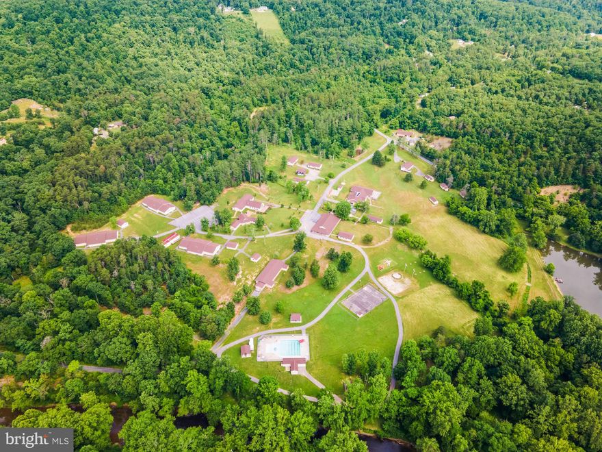 An amazing property being offered for sale on behalf of an international non-profit organization!  Welcome to Camp Tomahawk, a complete, modern retreat center and campground in the beautiful pastoral mountains of West Virginia.  This turnkey, fully operational campground offers everything from high-tech conference and chapel buildings to commercial-grade kitchen, dining, meeting, classroom, and recreational facilities for up to 300 guests.  There are three fully-furnished, comfortable homes for company directors and officials to live in with their families while at the property.  The main conference building itself offers hotel-style rooms for twenty guests, while two additional buildings provide plenty of room for staff housing.  There are three large bunkhouses for campers and counselors, plus a camp caretaker’s residence.  The property is 168 deeded acres and the camp is certified by the American Camp Association (ACA).  Recreational amenities include an event barn for program activities, a swimming pool, a campfire ring with bleacher seating, a pond for fishing and boating, a mountaintop observation tower, several picnic pavilions, two ropes courses, and numerous sports fields and outdoor activity stations.  This secluded retreat is well suited for a variety of corporate, private, and charitable uses, including hosting leadership meetings and staff teambuilding adventures.  It has been serving for 40+ years as a youth campground and is well known and loved by the surrounding communities.  The property is located only 15 minutes from Interstate 81 and Martinsburg, WV and about 30 minutes’ drive from Winchester, VA, Hagerstown, MD, and Charles Town, WV.  Guests will feel their stress melt away as they drive the scenic country roads leading to the camp, leaving behind the crowds and congestion of the daily grind.  When they arrive and turn in through the gates, they’ve found an opportunity to relax and recharge.