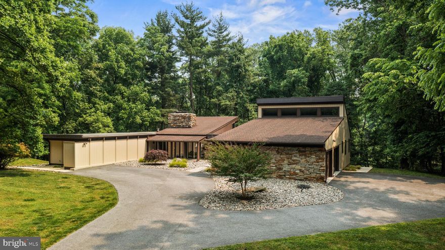 A remarkable mid-century vision brought to life in a perfectly-suited lightly wooded setting offering a large primary suite & 2-car oversized garage addition plus all the natural elements you expect in this stylish architectural concept.  Walls of glass and stone frame the entrance to this spacious ranch-style home and truly bring the outdoors into the interior experience. The living room features a soaring vaulted ceiling,  one wall of glass overlooking the deck and tree canopy beyond plus a floor-to-ceiling solid stone fireplace.  The kitchen offers abundant custom cabinet space, Ukrainian beveled edge Blue Vulga granite countertops and stainless steel appliances. A recent addition has created a sprawling owners' suite with copious closet space featuring California Closets organizers, soaring vaulted ceiling with clerestory windows and an impressive Carrera marble luxury primary bath.  A spacious walk-out lower level offers fantastic entertaining and recreation space and includes a wet bar, stone fireplace and half bath. Gorgeous newly-renovated bathrooms throughout. Enjoy the two composite decks on the rear and side of house. Make this mid-century retreat your new place of respite and relaxation!