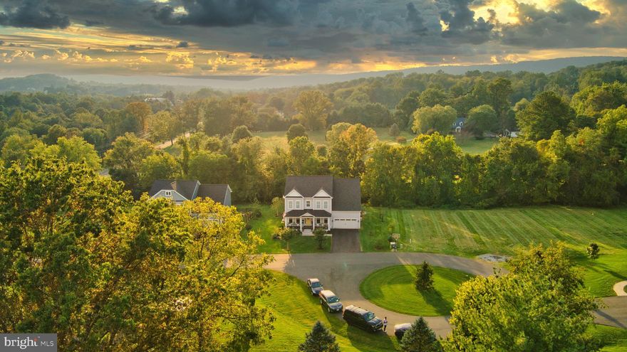 This semi-custom home built-in 2015 (with NO HOA & Fiber Optic Internet) is the one you have been waiting for. Conveniently located right in the charming town of Round Hill, the property is just under an acre with a scenic creek to enjoy and an open floorplan on 3 finished levels, totaling over 5200 square feet.  You will love the covered front porch with metal roofing and Trex decking for easy maintenance. When you enter the home, you will notice the rustic reclaimed oak floors from Cochrans Lumber, made from blackboard fencing and filled with character and tons of interest, the HW runs throughout the main level and up to the second story hallway. The gourmet kitchen boasts custom cabinetry, honed granite, SS appliances with a microwave drawer, and a luxury Bertozzoni Italian Range with 6 burners and a Carrara marble backsplash. A large walk-in pantry helps keep the kitchen counters free of appliances and food storage and the convenience of the separate butler's pantry helps establish a place for all your serving ware. A large mudroom with custom built-in lockers and a large coat closet is a dream come true for the busy lifestyle of work, school, and play. In the family room, there is plenty of space to gather and entertain with a gas fireplace, coffered ceilings, and a wall of windows that leads out to the scenic backdrop. Separate dining room, living room, and main level office complete the expansive main level. On the upper level, you will find 4 bedrooms, 3 baths, and a separate laundry room. In the primary owner's suite, there are 2 walk-in closets, a luxurious oversized bathroom with tons of storage, a soaking tub, and a freestanding shower with Carrara porcelain tile. The lower level is fully finished with walk-up access, luxury vinyl plank throughout, an electric fireplace with custom shiplap surround and rustic mantel, a gorgeous kitchenette with custom cabinets, quartz countertops, and a full-sized SS refrigerator. Generously sized 5th bedroom with walk-in closet, and full bath make this space ideal for an au-pair suite, generational living, or potential Airbnb opportunity.  This home boasts many outdoor living areas that you will cherish. Generously sized Trex deck that leads you to oversized stamped concrete patio with covered gazebo and custom firepit. Why build new when this one is ready NOW?