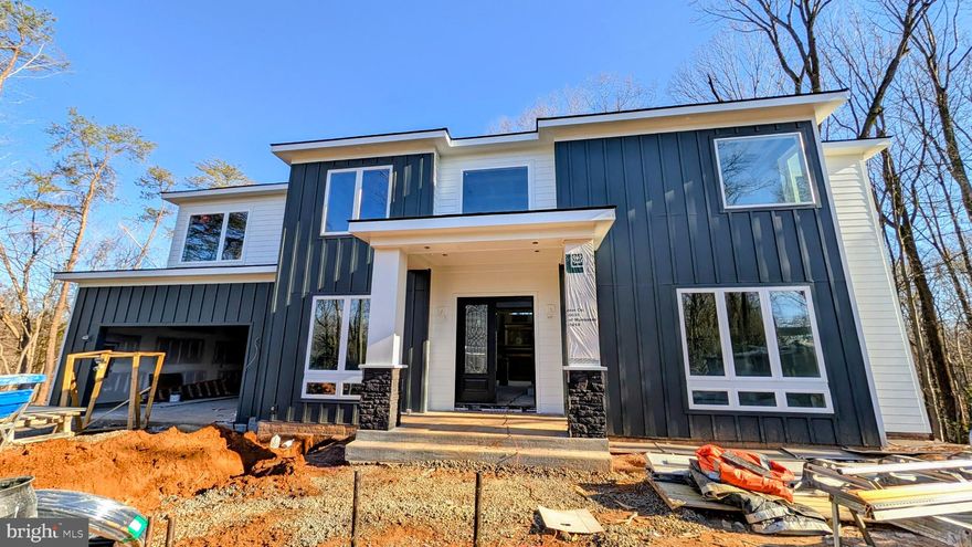 UNDER CONSTRUCTION: Sleek Modern Custom Home with Luxury Finishes in Manassas – Estimated Delivery  Late February 2026!
Builder is offering a $10,000 closing cost credit, plus an additional 0.50% of the loan amount when using the preferred lender and title company. 
Buyers who ratify by November will still have the opportunity to customize interior finishes, giving you a rare chance to personalize your dream home before construction progresses too far.

Get ready to fall in love with this expanded version of our highly popular model, offering even more space and flexibility across three beautifully designed levels. Nestled on a 1.17-acre corner lot, this approximately 5,800 sq ft, 6-bedroom, 6.5-bathroom modern masterpiece blends luxurious finishes with thoughtful design, perfect for today's lifestyle.

As you enter through the impressive two-story foyer, you'll immediately notice the natural light pouring in through oversized casement and picture windows, highlighting the soaring ceilings—10 feet on the main level, 9 feet upstairs, and 9 feet in the walkout basement—creating a truly grand and airy feel throughout.

The expansive main level features a guest bedroom with a private full bathroom, along with a separate powder room for guests. At the heart of the home is a stunning two-story great room, anchored by massive picture windows and a sleek modern fireplace that makes a true architectural statement. The adjacent gourmet kitchen is a showstopper, designed with both style and function in mind, featuring top-tier ZLINE appliances—including a 36” gas range and oven, 48” professional-grade range hood, and stainless dishwasher and microwave—or comparable high-end models to ensure the highest quality. A large waterfall island adorned with Calacatta Quartz countertops, a farmhouse-style sink, and 42” maple Vita white shaker cabinets with transom uppers complete the kitchen’s magazine-worthy look.

Upstairs, the luxurious layout continues with four generously sized bedrooms, each offering en-suite bathrooms for ultimate comfort and privacy. The primary suite is a true retreat, boasting a spa-inspired bathroom complete with a freestanding tub, elegant dual vanities, and a frameless glass shower with dual rain showerheads—the perfect place to unwind.

The finished basement adds even more flexibility, featuring a sixth bedroom and full bathroom, ideal for guests, extended family, or creating a future media room, gym, or office. With the expanded floorplan offering approximately 400 additional square feet compared to the previous build, every level of this home feels spacious, open, and thoughtfully designed.

Step outside to a covered 20’x18’ Trex deck with sleek steel railing, providing the perfect spot for morning coffee, evening wine, or entertaining guests. Built with durable Hardie Plank siding and PVC trim, the exterior is designed for both beauty and low maintenance for years to come.

This home offers a rare combination of modern luxury and custom craftsmanship, all within easy reach of major commuter routes and the charming Historic Town of Clifton. Whether you are searching for everyday elegance or a stunning forever home, this property will exceed your expectations.

Disclaimer: Photos are from a previously completed home of a similar model. Finishes, selections, features, and options may vary in the final construction. Please consult the listing agent for details.