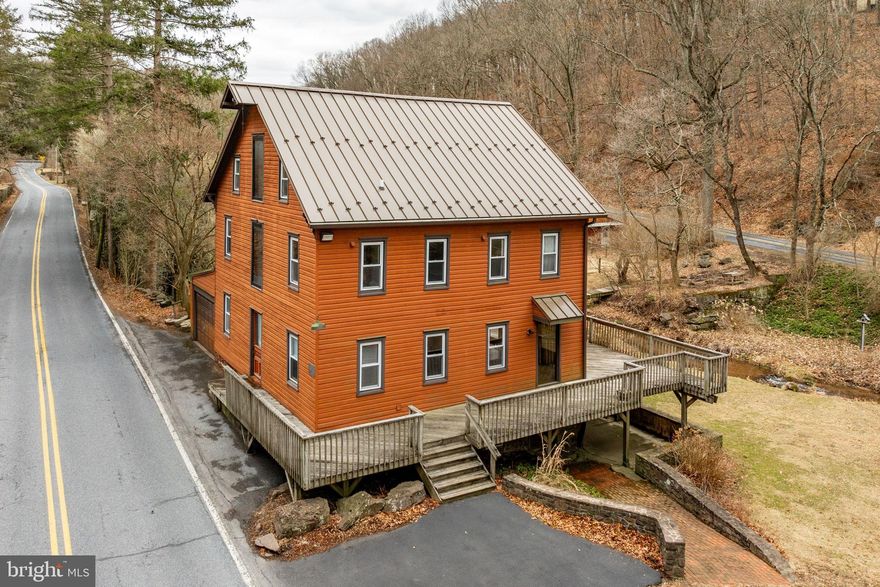 This is your chance to own a piece of American history, available for the first time in over 35 years! As the last standing Gun Makers Mill, this meticulously maintained barn-style home nestled along the picturesque Wyomissing Creek, seamlessly blends original character with modern upgrades. The property offers a spacious barn with two stalls and additional animal spaces, all enclosed by an electric fence for safety, while providing plenty of room for livestock to roam freely, including a spring fed pond and lush grassy pastures. A separate chicken house is also ready for you to start raising chickens and enjoying fresh eggs. For extra space, the former two story mill barn converted into a large detached two-car garage with a loft provides versatile storage or hobby space. As you approach the home, you’ll be welcomed by a large wrap-around deck, ideal for relaxing and enjoying the serene creek views, the sounds of nature, and the wildlife that surround the property. Inside, the open kitchen has been thoughtfully remodeled to offer ample space while still complementing the mill’s original charm, including stunning original wood floors and a beautiful wood-beam ceiling that create a, warm, inviting atmosphere. The first floor also features a flexible room perfect for a home office or gym, bathed in natural light with views of the creek. For added convenience, there’s a main-floor laundry area, a half bathroom, and a walk-in pantry that leads to the garage. Upstairs, you’ll find four spacious bedrooms, including a primary suite with its own private bathroom and luxurious steam shower. A second full bathroom and a striking barn door, which opens to the front of the home and floods the upstairs with natural light, complete this floor. The third floor features the largest room in the house, showcasing the original mill pulley, a unique piece of history that still stands strong. Skylights and the front barn door fill this space with light, making it an ideal area for relaxation or creative pursuits. Don’t forget to explore the walk-out basement, where you can admire the authentic stone foundation of the original mill. Equipped with modern improvements like the newer standing seam metal roof, an upgraded HVAC system, and on demand hot water, this home is a rare and exceptional find that beautifully combines history, charm, and modern comfort, offering a truly unique living experience. Schedule your visit today to see all that 833 Wyomissing Rd has to offer!