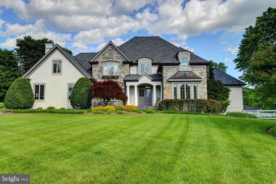 Nestled in the countryside just outside Clifton, this exquisite French country-inspired estate combines timeless charm with modern luxury, delivering an exceptional lifestyle for equestrians and lovers of refined rural living. Constructed with rich stone and stucco finishes, the home exudes both sophistication and warmth..

The heart of the home is an elegant, thoughtfully designed kitchen featuring classic white custom cabinetry, expansive granite countertops, and a versatile layout that includes both an island and peninsula with bar seating. An adjacent sunlit breakfast room opens through French doors to a peaceful patio—ideal for relaxed indoor-outdoor dining and enjoying the serene landscape.

A spacious and well-appointed laundry room offers abundant cabinetry and extra counter space, doubling as a practical prep area for entertaining. Flowing seamlessly from the kitchen is the inviting family room, anchored by a stately fireplace framed with custom built-ins, perfect for cozy gatherings or quiet evenings.

The formal areas of the home elevate its elegance: the dining room is highlighted by a bespoke hand-painted mural depicting the estate’s sweeping vistas (and a hidden fox to find!), while the oak-paneled study and refined living room add depth and character to the interior.

Upstairs, the primary suite is a private sanctuary, offering two separate sitting rooms and dual walk-in closets with space for expansion. The luxurious ensuite bath includes dual vanities, a jetted soaking tub, separate shower, and a private water closet. The "Princess Suite" showcases beautiful architectural details and its own ensuite bath. In total, there are four upper-level bedrooms with gleaming hardwood floors and three full baths.

The fully finished lower level is designed for entertainment and relaxation, featuring a cozy fireplace, wet bar, recreation room, and billiards table— which may convey. French doors lead to a charming sunken patio with a brand-new hot tub, offering an idyllic retreat. A spacious fifth bedroom and a fourth full bath complete this level.

Equestrian amenities are truly world-class. The custom-built Morton eight-stall barn was designed with both form and function in mind, offering swing-out feeders, a heated tack room, laundry facilities, a hot/cold wash stall, and a hay loft.  The 8-stall barn that could easily be reimagined as a 7-car collector’s garage with loft accommodations.   Meticulous attention to airflow includes a ventilation fan and three decorative cupolas. Five large pastures, bordered by traditional white three-board fencing, and a professional 100x200 bluestone and rubber riding arena with a full-width mirror provide everything needed for serious training or casual riding. The barn’s covered front porch—perfect for relaxing while overlooking the grounds—may just become your favorite vantage point.  Home has dog-friendly perimeter featuring a classic three-board fence reinforced with discreet wire mesh. 

Additional features include a new roof and gutters (2019), brand-new Pella windows (2024), an oversized three-car garage, central vacuum, four-zone heating across the main and upper levels, and abundant storage throughout.