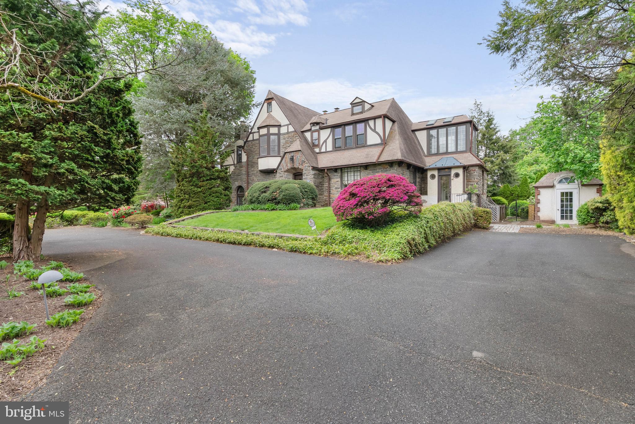 For the discerning buyer seeking a one-of-a-kind home overflowing with distinctive character, abundant space, and magazine-worthy architectural details, 8300 Cedar Rd presents an enticing offer. Sitting on a sprawling half-acre corner lot, this 5,072 sqft Tudor home has 4 bedrooms, 4.5 bathrooms, a finished basement, multiple flex spaces, 2 sunrooms, a sauna, a patio, and a private backyard. A curved driveway guides you through the manicured lawn, lush shrubbery, and mature trees toward the stone exterior's main entry. Inside, a vestibule leads you to a foyer. To the left, a wrought iron railing overlooks the grand living room that is the showpiece of the home. Framed by beautifully aged hardwood floors and soaring ceilings with exposed beams, a curved staircase descends into the bright and airy space where stained glass windows, beveled glass French doors, and a plaster fireplace add interest to every corner. Off the living room is a study with built-ins and a huge sunroom displaying picturesque views of the grounds. To the right of the main foyer, dark wood trims the large dining room that has ample space for entertaining friends and family. An arched door connects to the gleaming gourmet kitchen, fitted with lots of cabinet and counter space, high-end appliances, and two sinks. A mudroom with a second entrance from the driveway sits off the kitchen. Completing the main level is a powder room and a family room with dramatic vaulted ceilings, a fireplace mantel, and sliding doors that open to the rear patio. Up on the second level, the hotel-like primary suite has a bay window bench, multiple custom closets, and a luxurious ensuite bathroom boasting dual vanities, a whirlpool tub, a glass-enclosed shower, and a water closet. Two more large, bright bedrooms, a second sunroom, and another full bathroom are off the hall. Topping the home is a large fourth bedroom with its own full bathroom. Bonus living space can be found in the expansive basement, where there are two flex rooms, a laundry room with exterior access, a full bathroom by the sauna, and a large unfinished space ideal for storage. In addition to everything inside, the lush backyard acts as a private oasis where you can spend cool spring days tending to your garden and host barbecues and al fresco dinners on warm summer nights. 8300 Cedar Rd's utilities include central a/c, gas heat, electric baseboard heat, and gas hot water. Brand new 5-Zone gas boiler installed February 2025 with brand new thermostats throughout and an extended warranty. This fantastic Elkins Park location is close to popular shopping centers, parks, universities, and medical centers. There's also easy access to Township Line Road and Old York Road. Schedule your tour today!