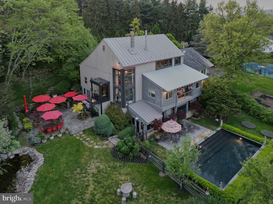 This stunning barn conversion seamlessly blends rustic charm with modern luxury. The 
barn and farmhouse date back to 1710. The character of the original barn has been
carefully preserved featuring the original exposed beams and magnificent stonework. 
Upon entering the home, you are greeted by a spacious open and flexible living area with 
soaring ceilings and large windows that flood the space with natural light. There are also 
radiant heated hard wood floors throughout this level. This designer decorated home is 
available fully furnished. A beautiful bright gourmet kitchen boasts high end appliances, a large center island and lots of counter space and custom cabinetry. The living room is spectacular with a magnificent Rumsford fireplace at its center. There is also a large dining area surrounded by windows overlooking the gardens. This floor also has a well-sized office and a full bath. The stone walls, wood beams and radiant heated floors continue to the lower level featuring an amazing primary suite which includes a large bedroom, gorgeous marble bathroom with mother of pearl mosaic floors, glass shower and soaking tub. A dressing hall features rows of closets and there is a sitting/dressing room with beautiful lit cabinetry. 
A balcony works perfectly as a home gym overlooking a sunroom and double doors out to 
the pool and gardens. The second floor includes 2 guest suites and a full bath. The third floor has an interesting, cozy space for either an additional bedroom or home office. The home also includes a 
completely private one-bedroom guest apartment with a full kitchen, living room and deck 
overlooking the gardens. The apartment is accessible from either inside the home or through its own private entrance with an elevator. Step outside to discover the extensive lush gardens and mature trees, creating a peaceful escape. The expansive Blue Stone terrace with outdoor kitchen is ideal for seasonal al 
fresco dining while overlooking the swimming pool complete with eight fountain heads. 
There is also a koi pond with waterfall and magnificent illuminated gardens. A tennis/pickle 
ball court completes the outdoor amenities. The home is conveniently located with a wide variety of shopping and dining options minutes away. Drive time to Princeton is 20 minutes, 40 minutes to Philadelphia and 70 minutes to NYC while the nearest train station is a 20-minute drive. 
Behind the gated entrance, Eight Bells is truly a private oasis located in one of Bucks 
County’s most prestigious/upscale towns. A perfect getaway retreat, this property promises a lifestyle of elegance and tranquility.