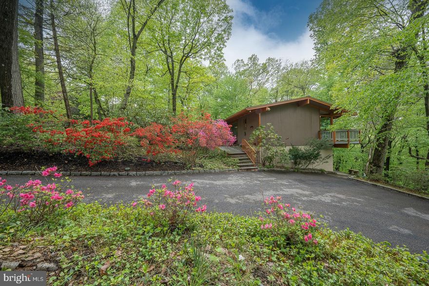 Watch the seasons change in this mid century modern style home rooted in functionality, clean lines, and simplicity. Lots of glass to emphasize bringing the outdoors in! Built by McElroy, designed by Rincon, this open floor plan has wonderful character, from a front courtyard with fieldstone walls, vaulted beam ceilings,  and brazilian hardwood floors. Enter through the sliding front door, into the Tree House with high ceilings, skylights, window walls and amazing natural light.  The open large living space is shared by the Living room and Office/Library room.  Both rooms open out to a large deck across the back of the house. Gourmet Kitchen with a floor to ceiling glass Breakfast Nook, Island, Laundry room with doggy door and Family Room with sliding glass doors to it's own deck. Convenient bridge crossing to a primary first floor Bedroom suite including  attached Studio and Bath, plus Laundry Room  complete first floor living. Lower level has three Bedrooms (or office), two Full Baths, and Great Room with sliding glass doors to outside patio. Wonderful sized storage area under addition. Upgrades include new HVAC in addition,  Generac gas generator. Security system.  Landscape irrigation system. 1 acre wooded lot within minutes to major roads, and the Main Line.